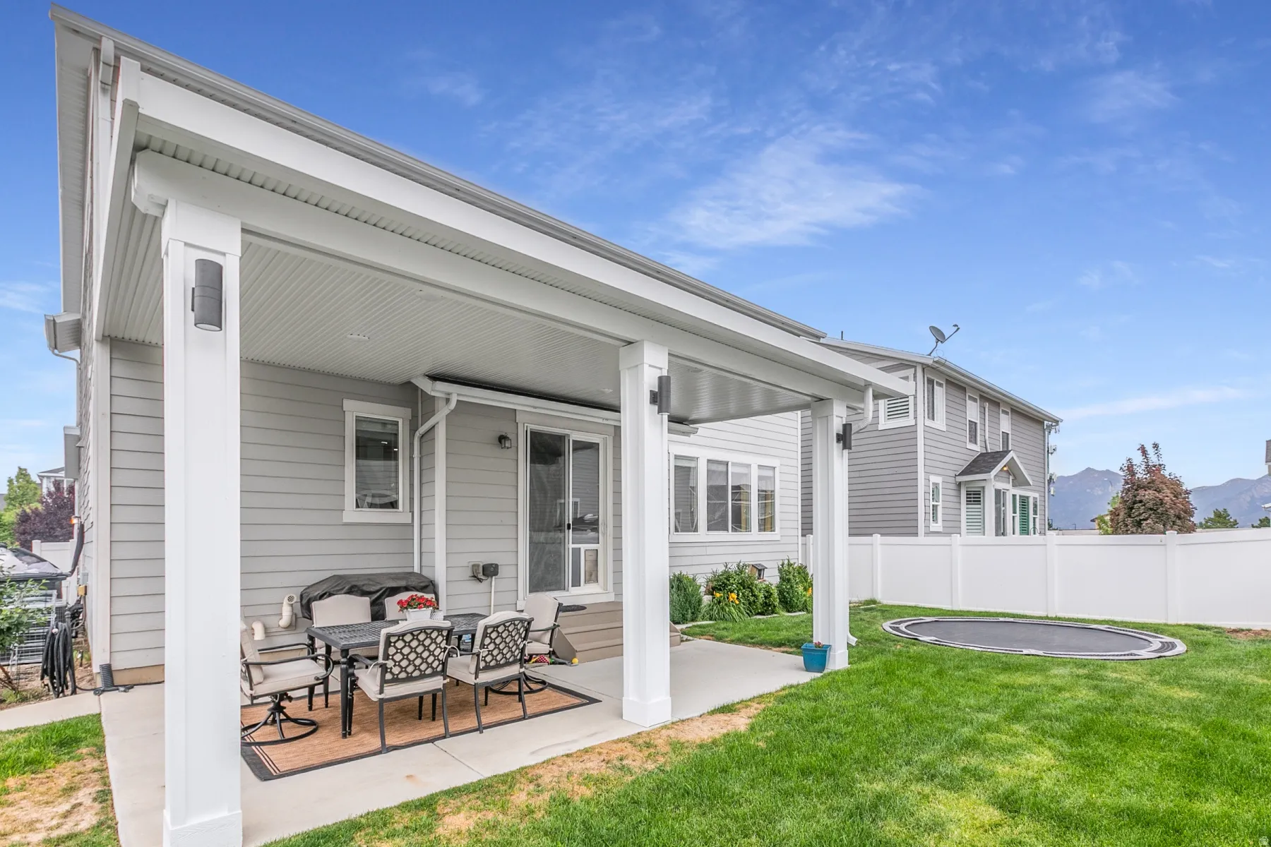 Covered concrete patio with white columns and exterior lighting
