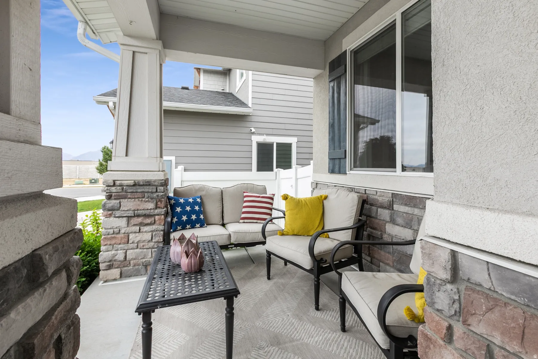 Covered front porch featuring stone veneer accents and stucco siding