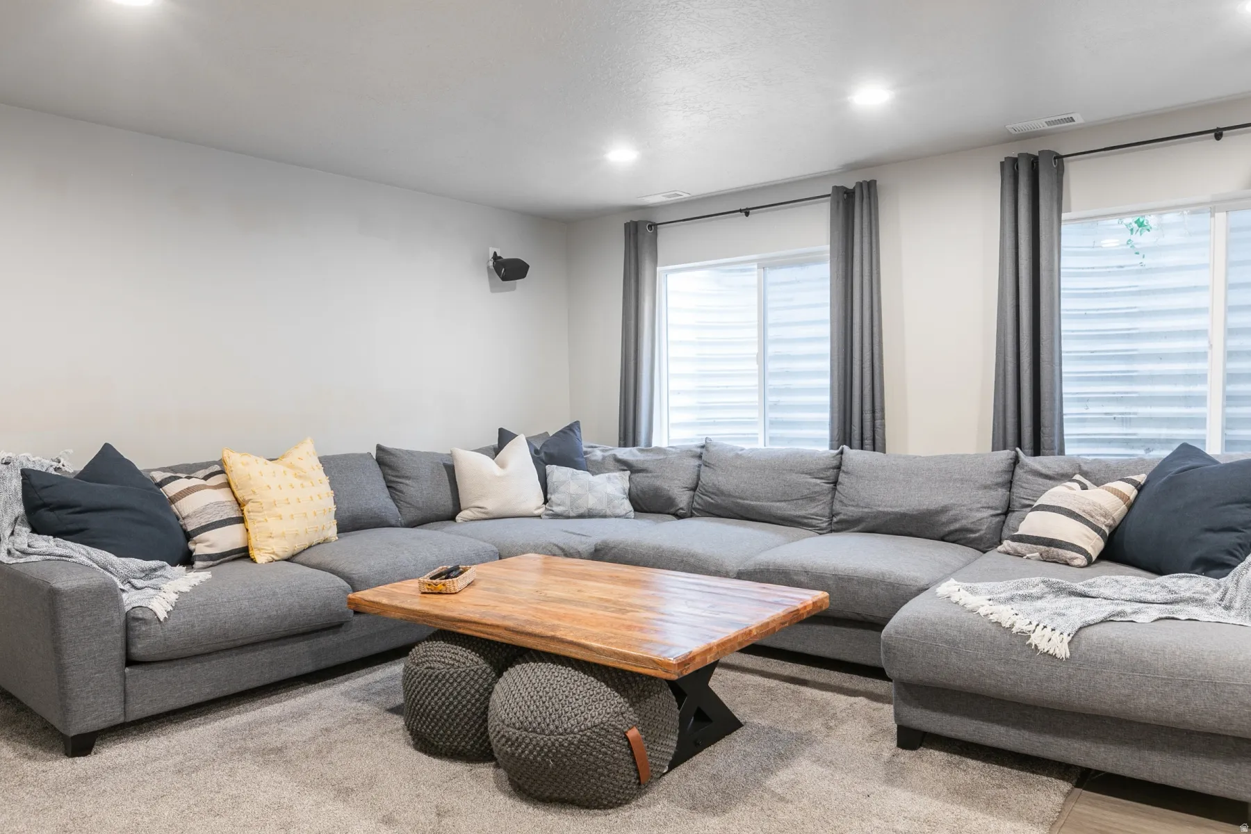 Spacious recreation room featuring recessed lighting, light gray walls, and two large egress windows with gray drapery