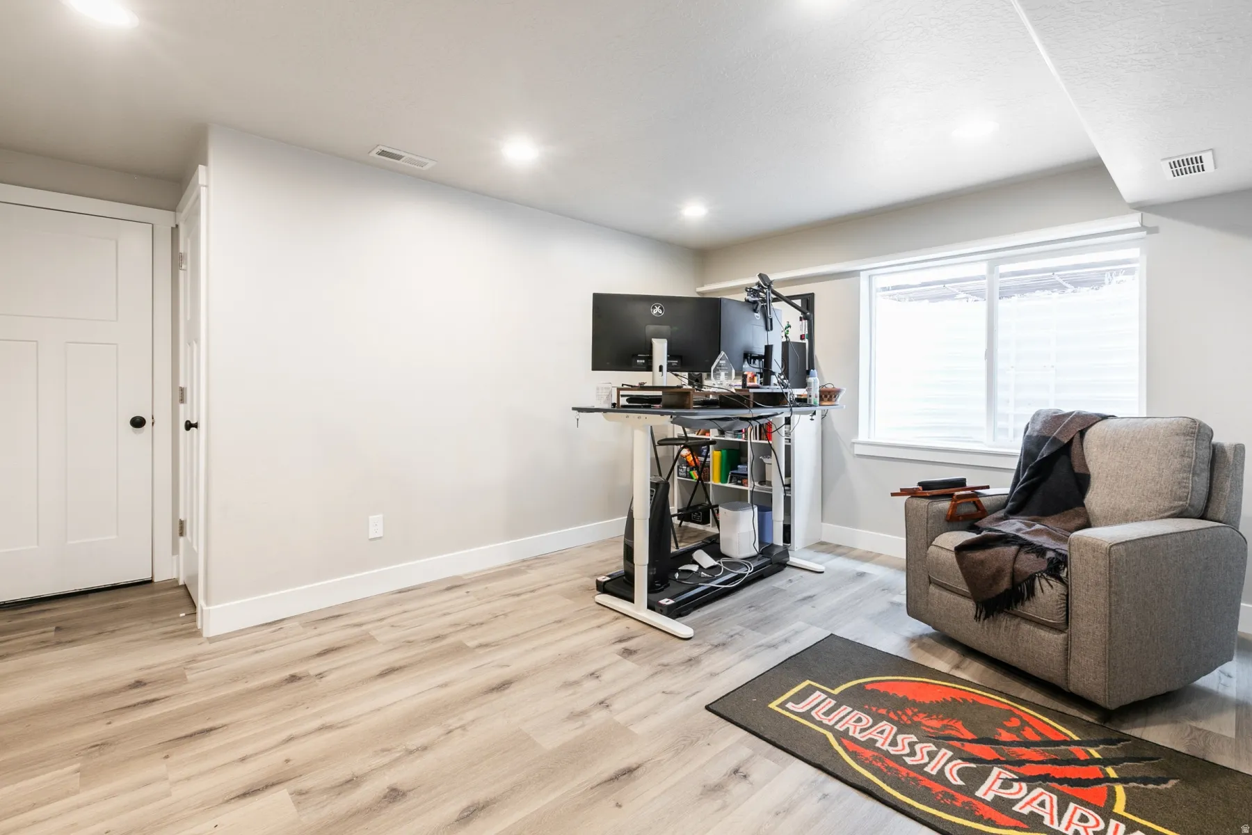 Spacious room featuring light wood-finish flooring, recessed lighting, and a prominent window