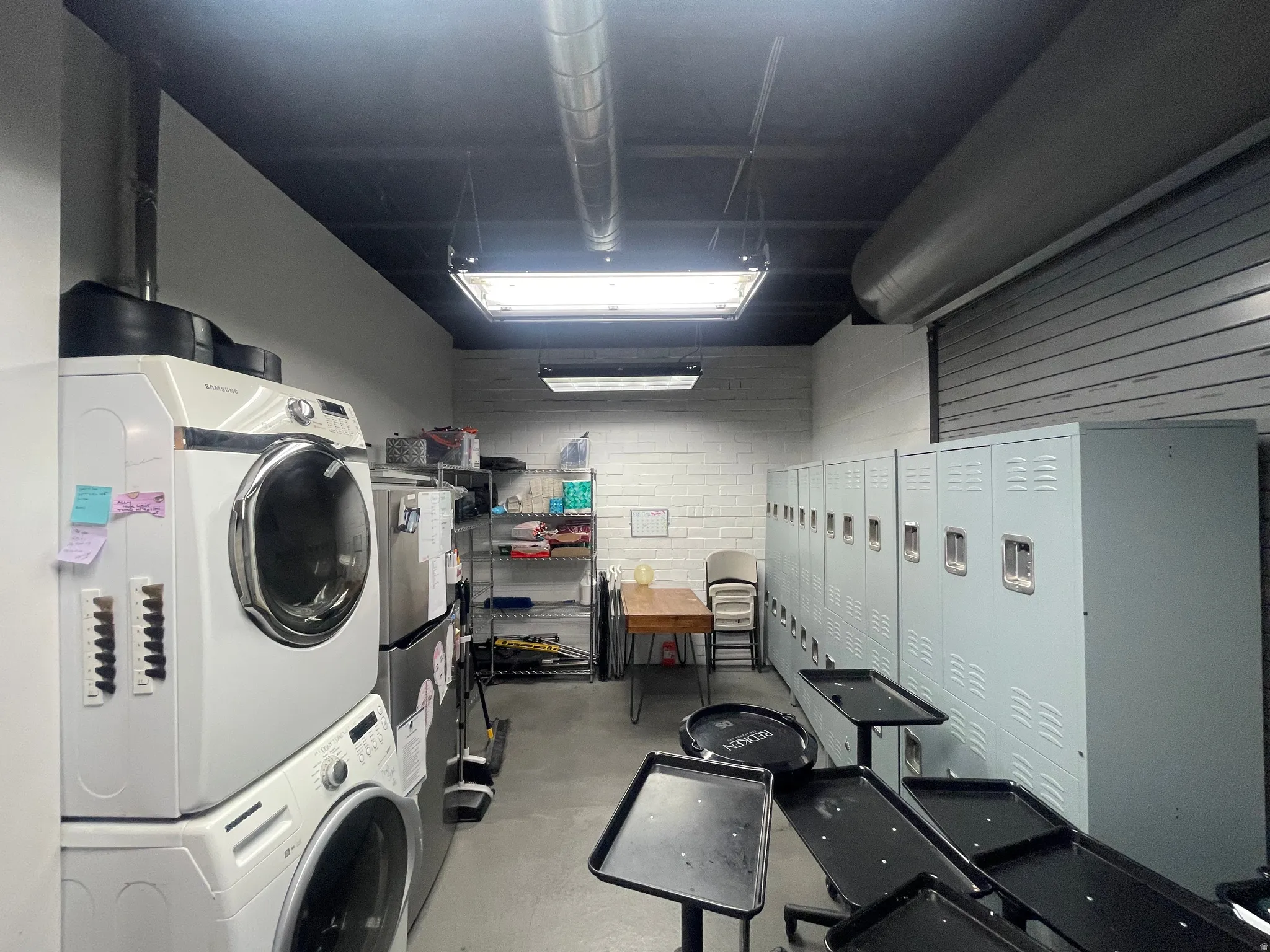 Utility room featuring white brick walls, exposed ductwork, and a dark ceiling