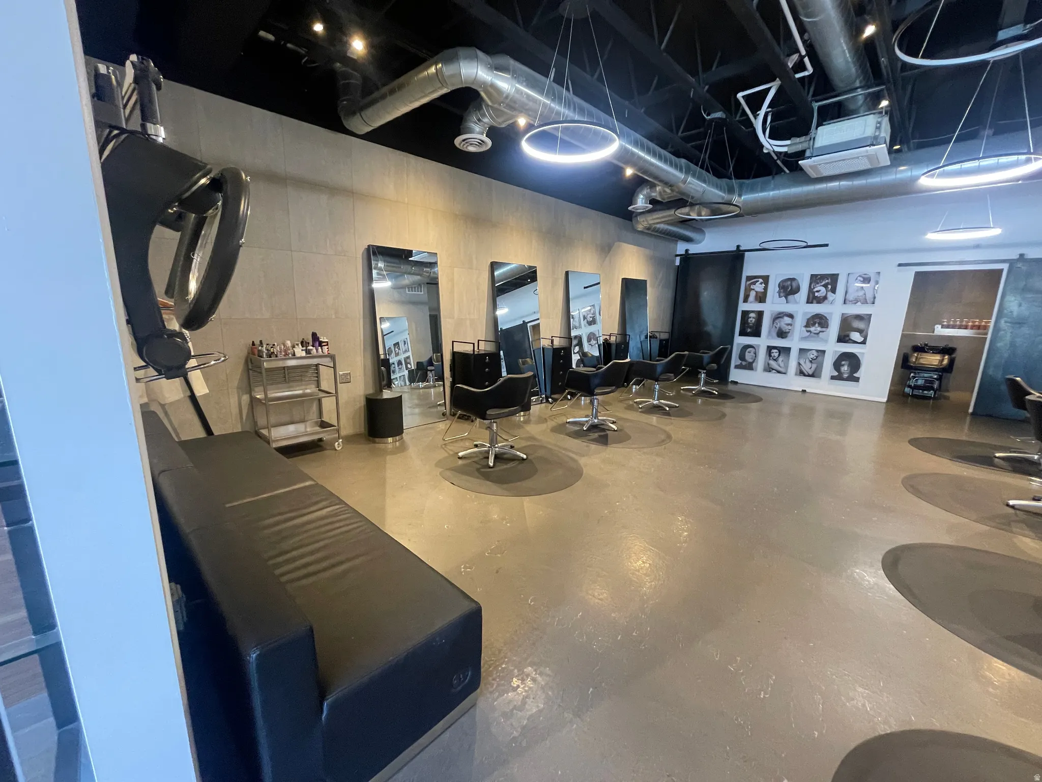 Open-concept commercial space featuring polished concrete flooring with circular accents, exposed industrial ductwork, and track lighting