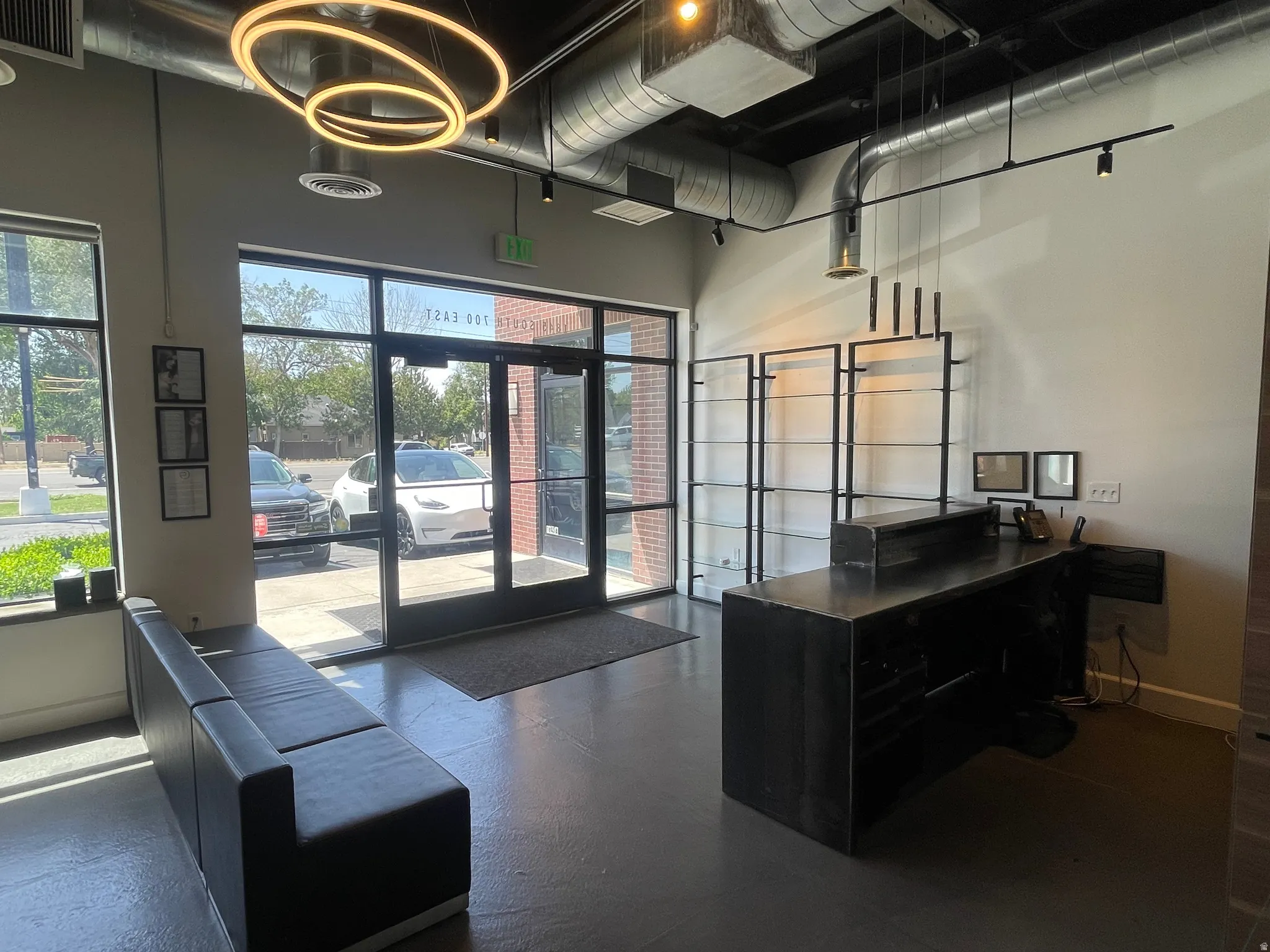 Spacious entry area with a full-light glass storefront, industrial-style exposed ductwork, and track lighting