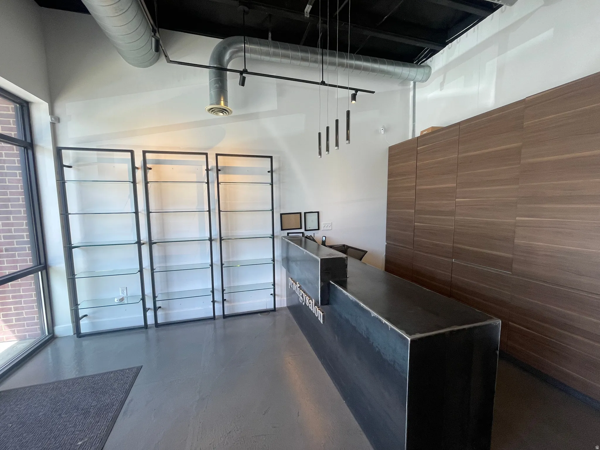 Industrial-modern reception area featuring a dark metal front desk and textured wood-panel wall