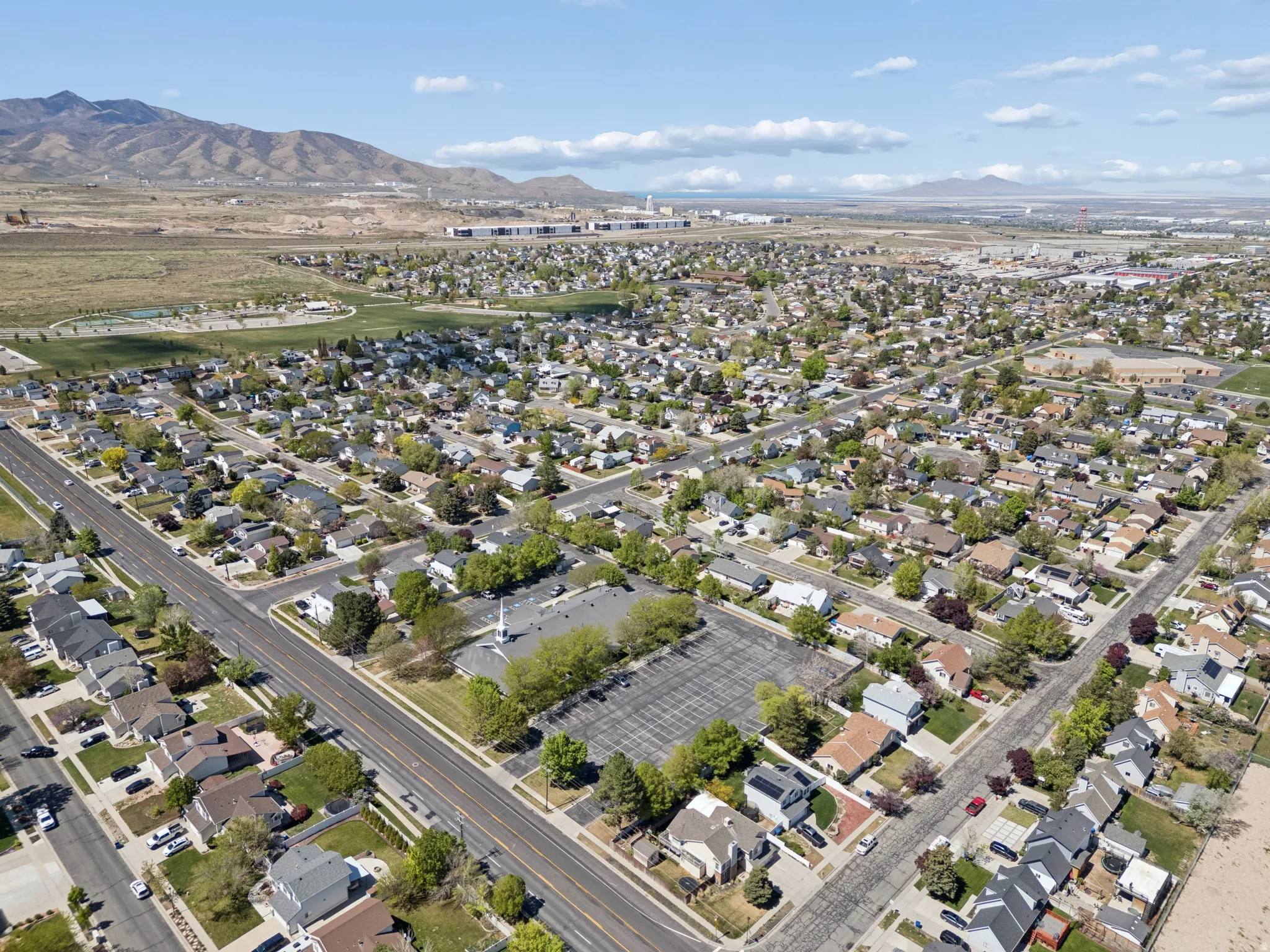Aerial perspective of a residential neighborhood with diverse architectural styles, mature trees, and paved streets.