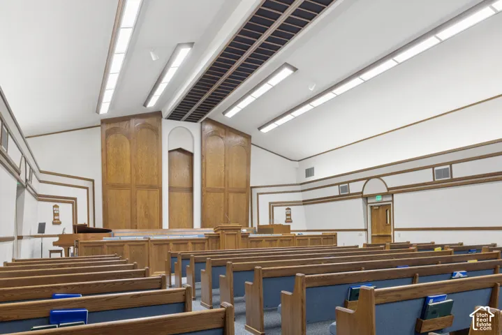 Spacious assembly room featuring extensive rows of wooden pews with blue upholstered seating.