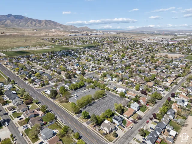 Aerial perspective of a residential neighborhood with diverse architectural styles, mature trees, and paved streets.