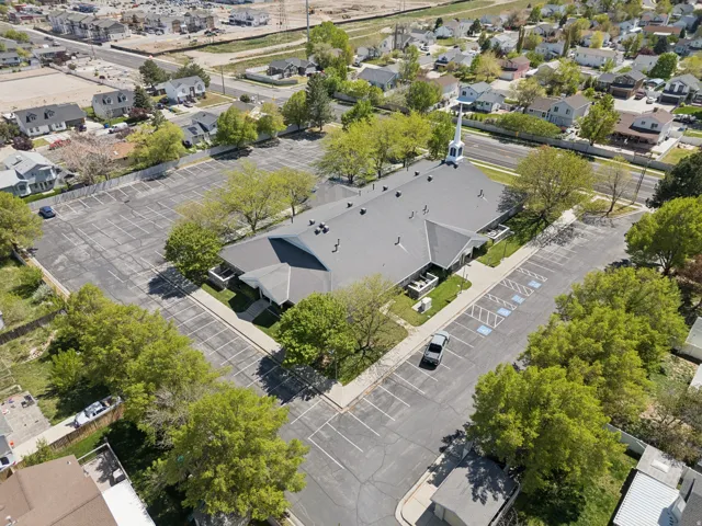 Expansive property featuring a large structure with a steeple, surrounded by a substantial paved parking area.