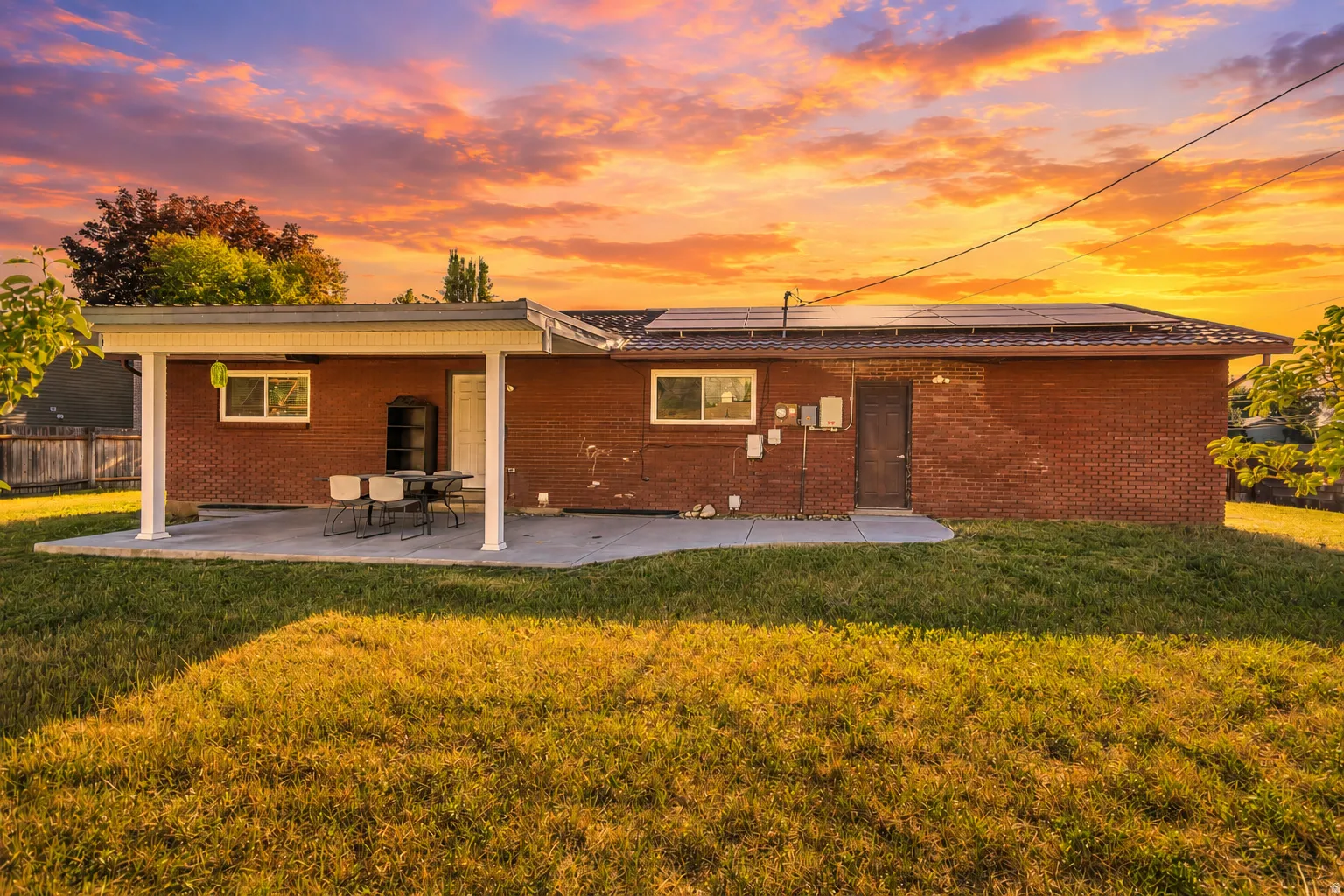 Brick exterior featuring a covered patio, concrete slab, and solar panels