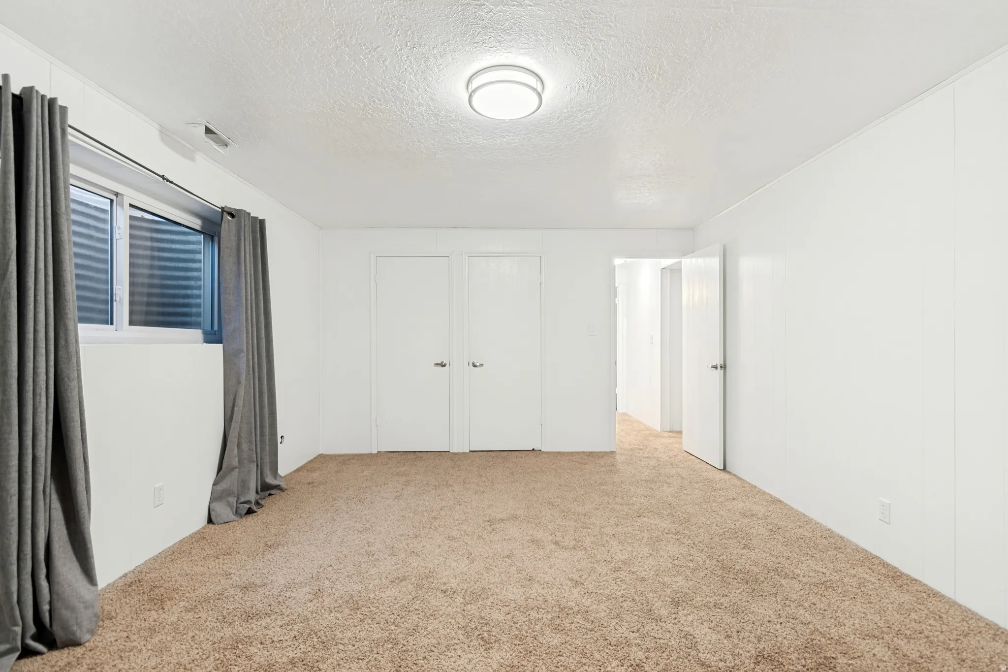 Carpeted room featuring white paneled walls and a flush-mount ceiling light fixture