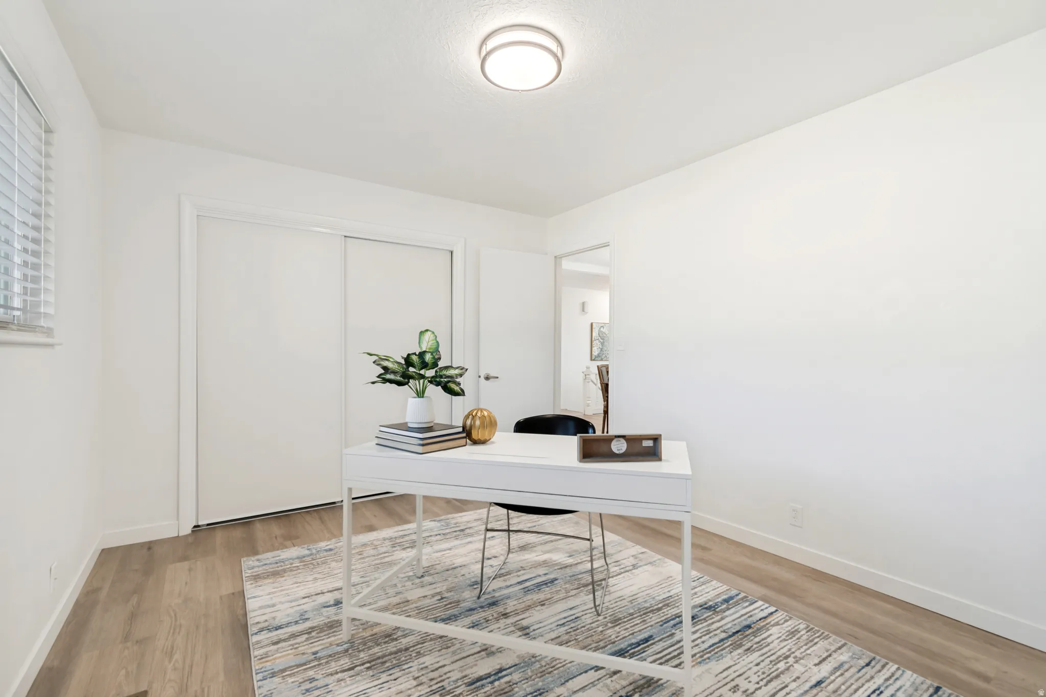 Bright room featuring wood-finish flooring, white walls, and a window with blinds