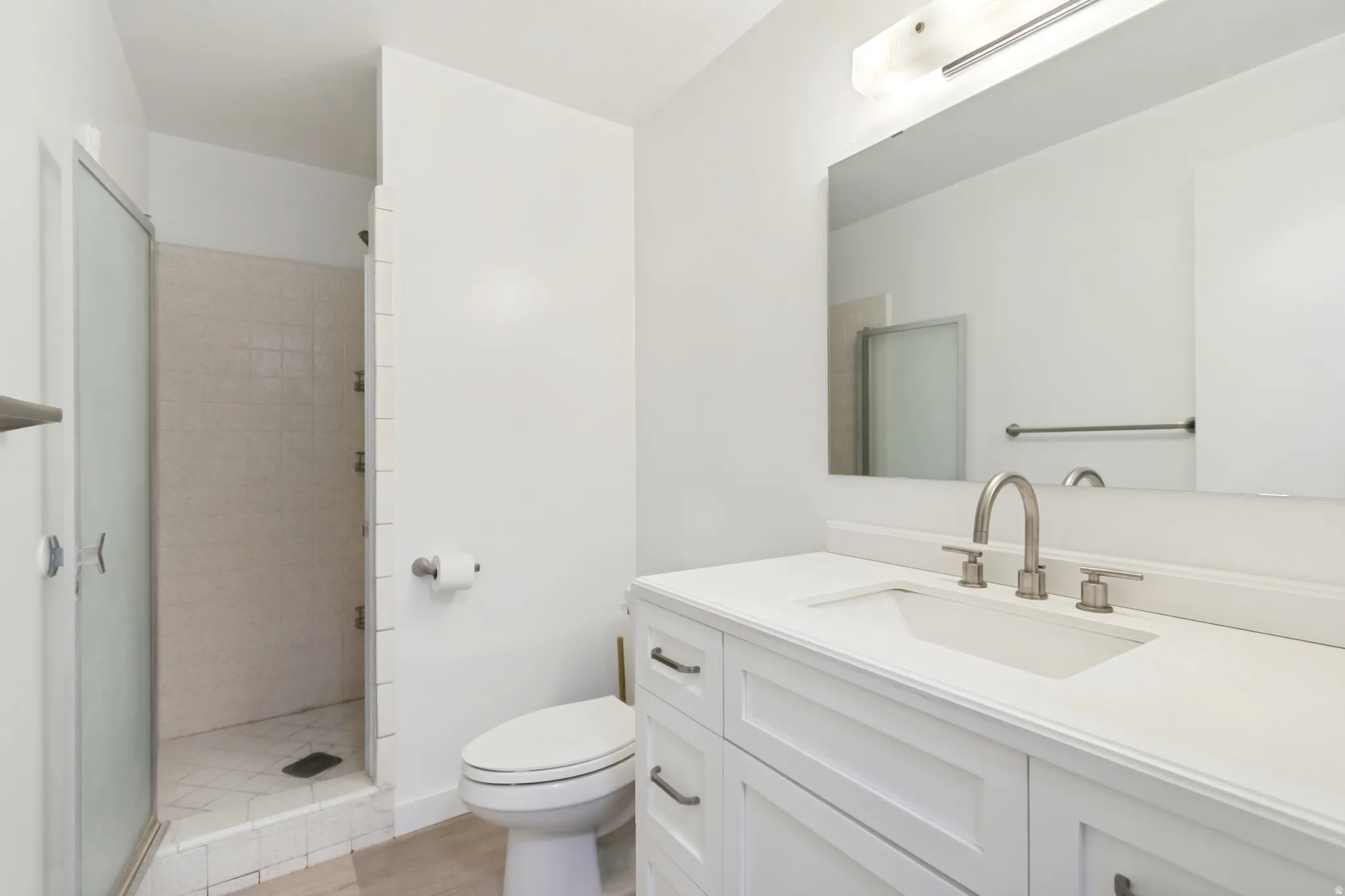 Bathroom featuring a white vanity with an undermount sink, brushed nickel faucet, large mirror, and overhead light fixture