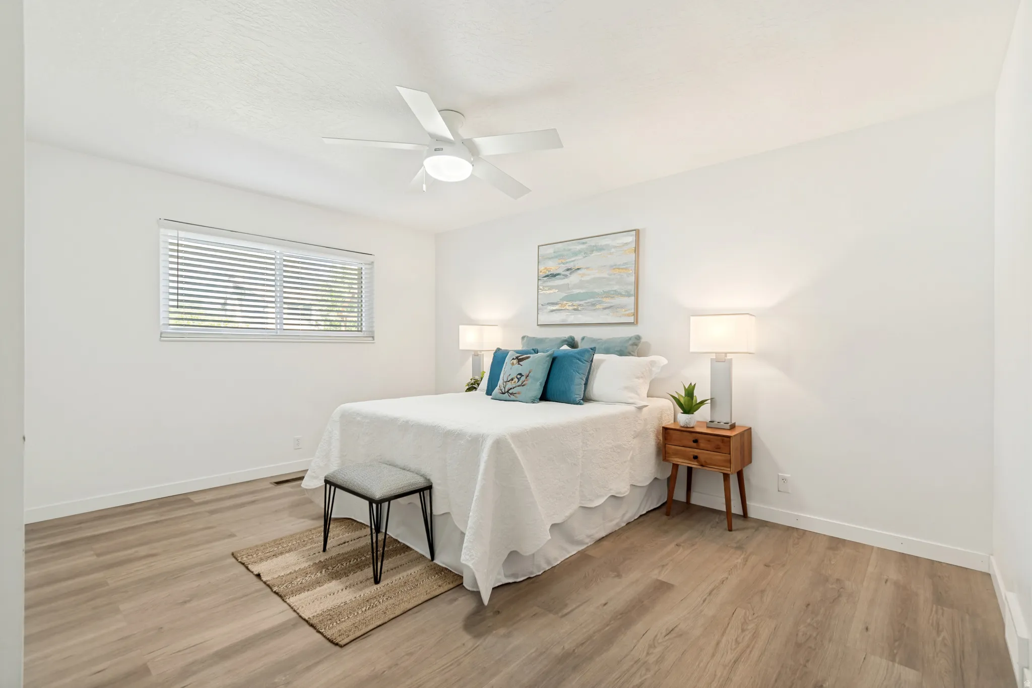 Spacious room with wood-finish flooring, a ceiling fan, and a window with blinds