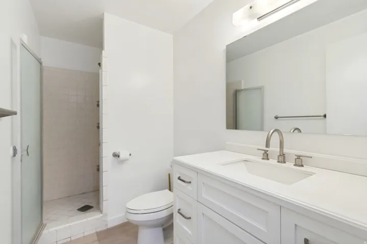 Bathroom featuring a white vanity with an undermount sink, brushed nickel faucet, large mirror, and overhead light fixture