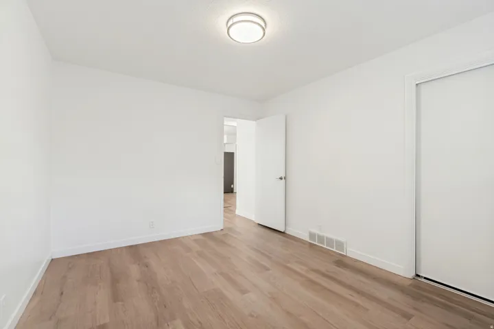 Bright room with wood-finish flooring, white walls, and a contemporary flush-mount ceiling light