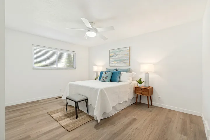 Spacious room with wood-finish flooring, a ceiling fan, and a window with blinds