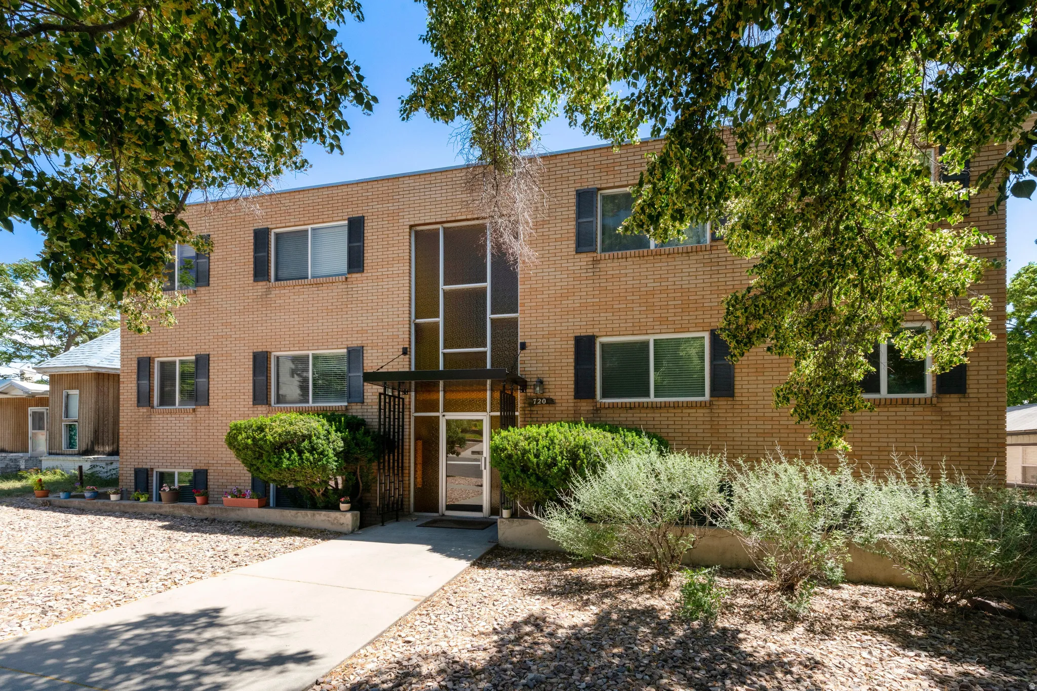 Brick exterior featuring black window shutters and a prominent glass entry