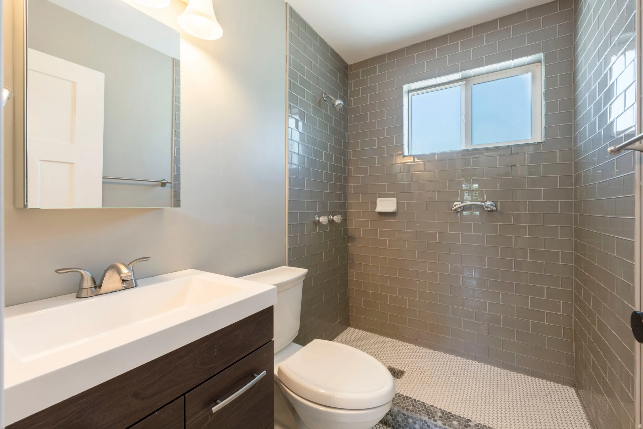 Bathroom featuring a modern vanity with integrated sink, rectangular mirror, and wall-mounted lighting