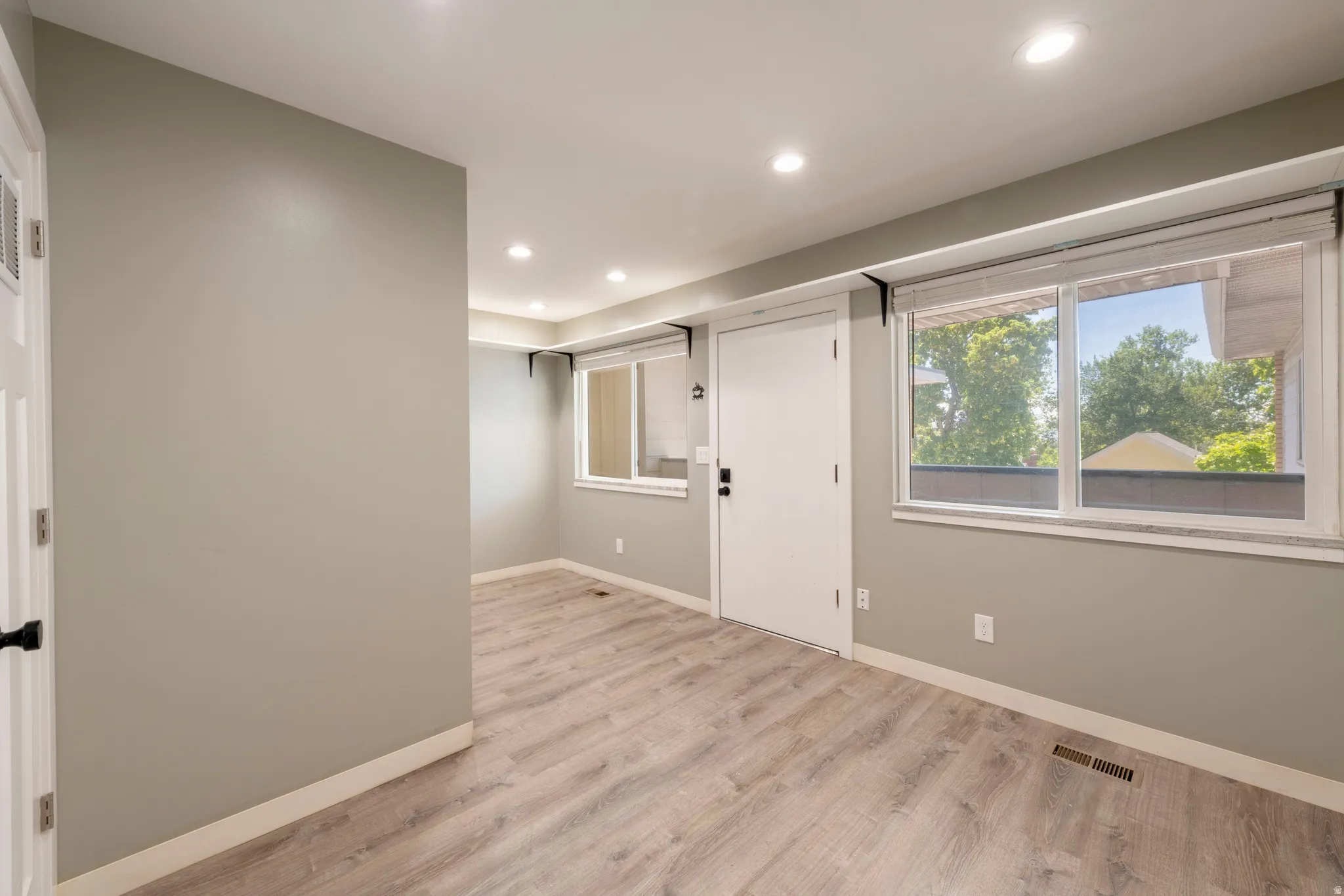 Open room featuring wood-finish flooring, recessed lighting, neutral wall tones, and multiple windows