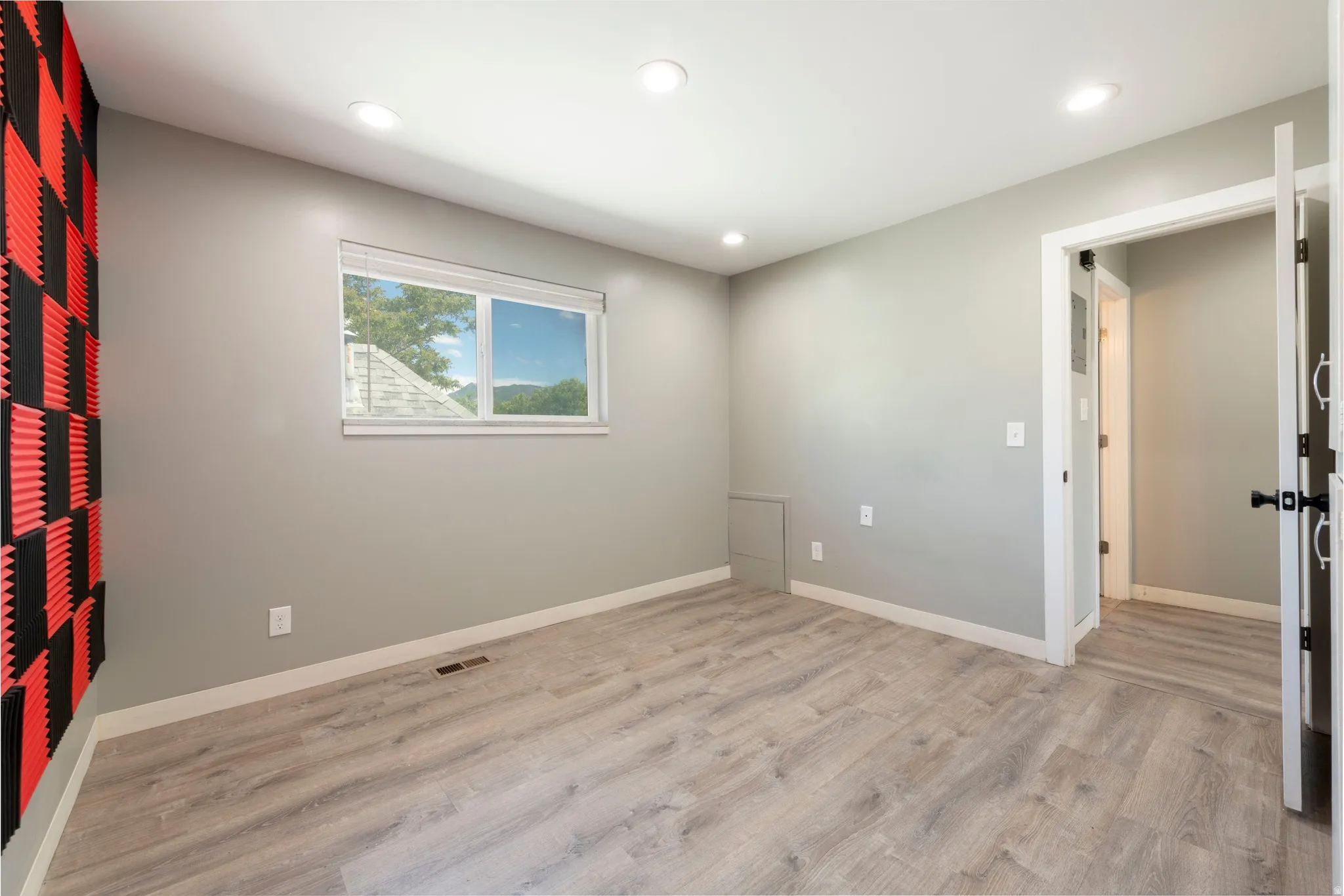 Spacious room featuring wood-finish flooring, recessed lighting, and a white trim window