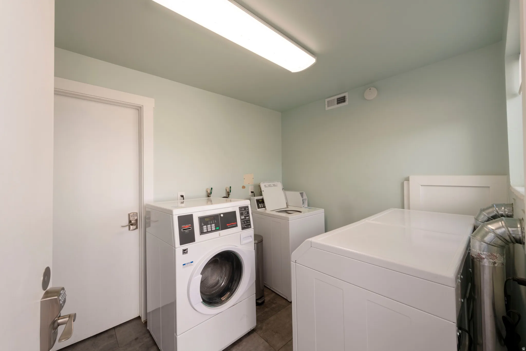 Dedicated laundry area featuring multiple washing machines and dryers