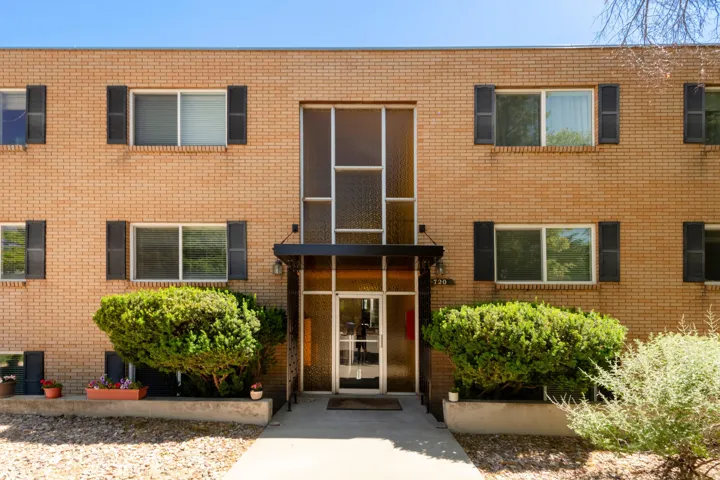 Brick facade building with black louvered shutters and a central glass entry