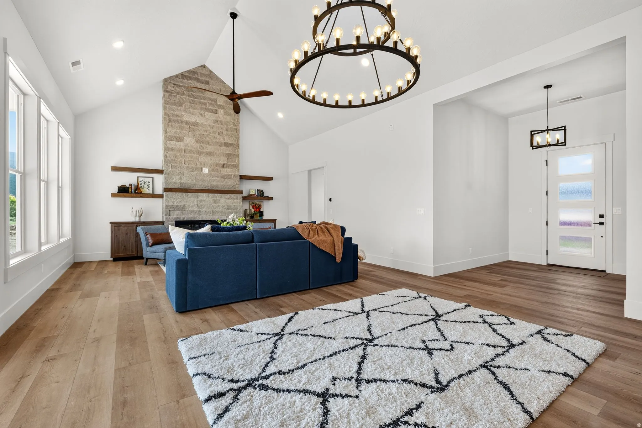 Vaulted ceilings with a stone fireplace and wood-finish flooring