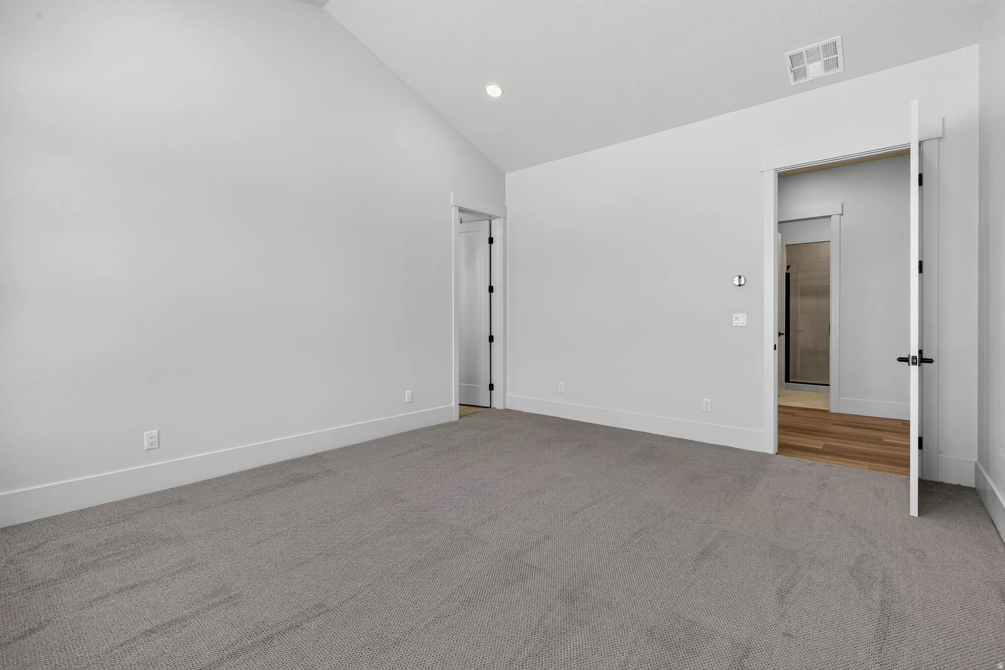 Primary bedroom featuring vaulted ceilings, recessed lighting, neutral wall tones, and gray carpeting