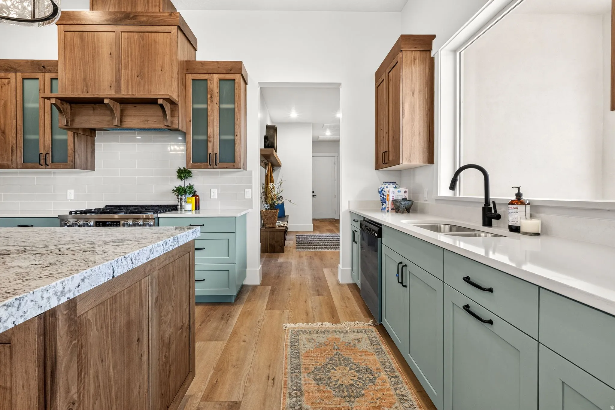 Gourmet kitchen featuring a granite-topped island, light wood-finish cabinetry, a subway tile backsplash, and light green lower cabinetry