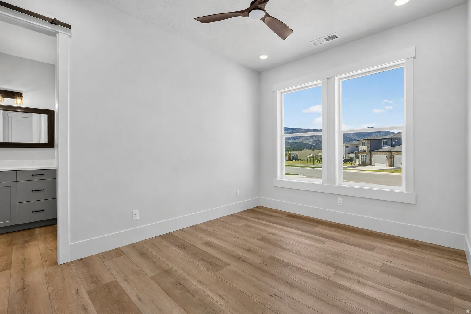 Spacious flex/office room featuring laminate flooring, a modern ceiling fan, and recessed lighting