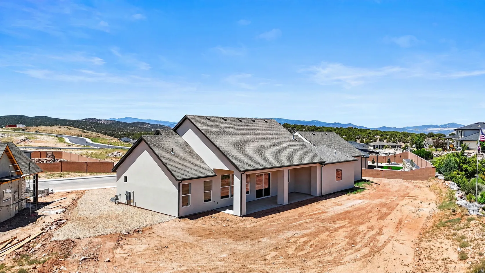 Contemporary home featuring a light-colored stucco exterior, multi-gabled roofline, and covered patio area