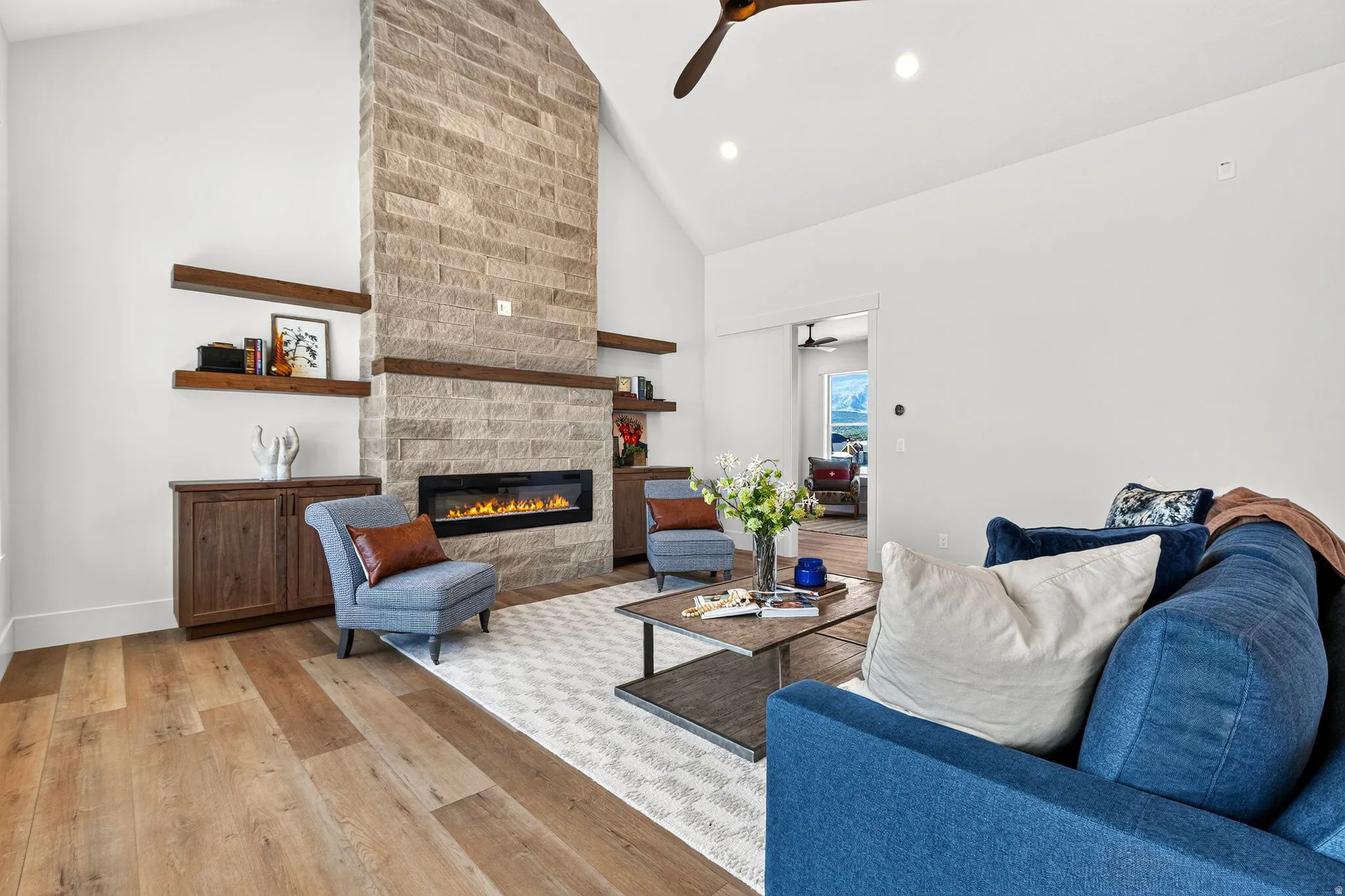 Stone-clad fireplace with a linear gas insert, flanked by built-in wood cabinetry and floating shelves