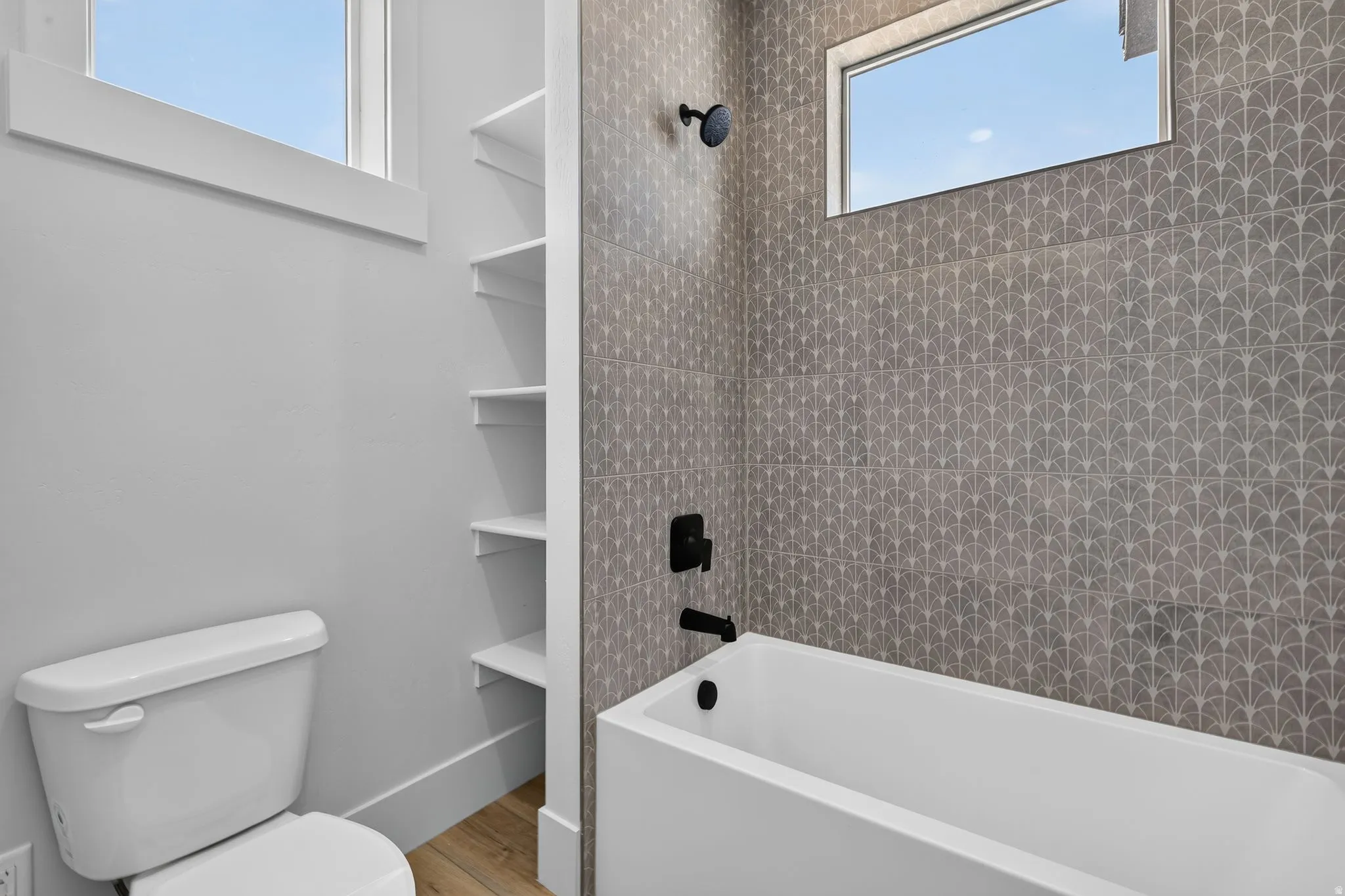 Contemporary bathtub with matte black fixtures and decorative tiled surround