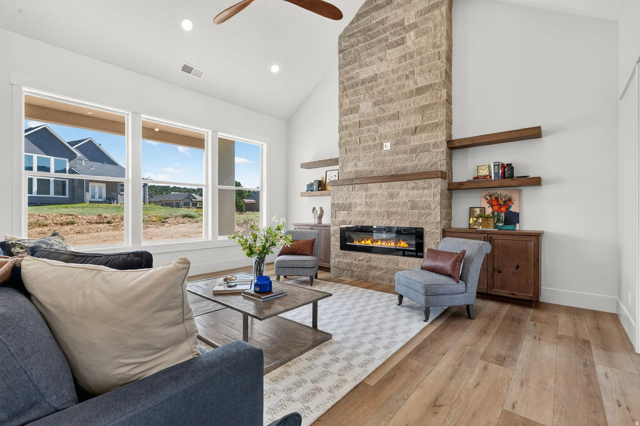 Vaulted ceilings above a floor-to-ceiling stone fireplace featuring an electric insert