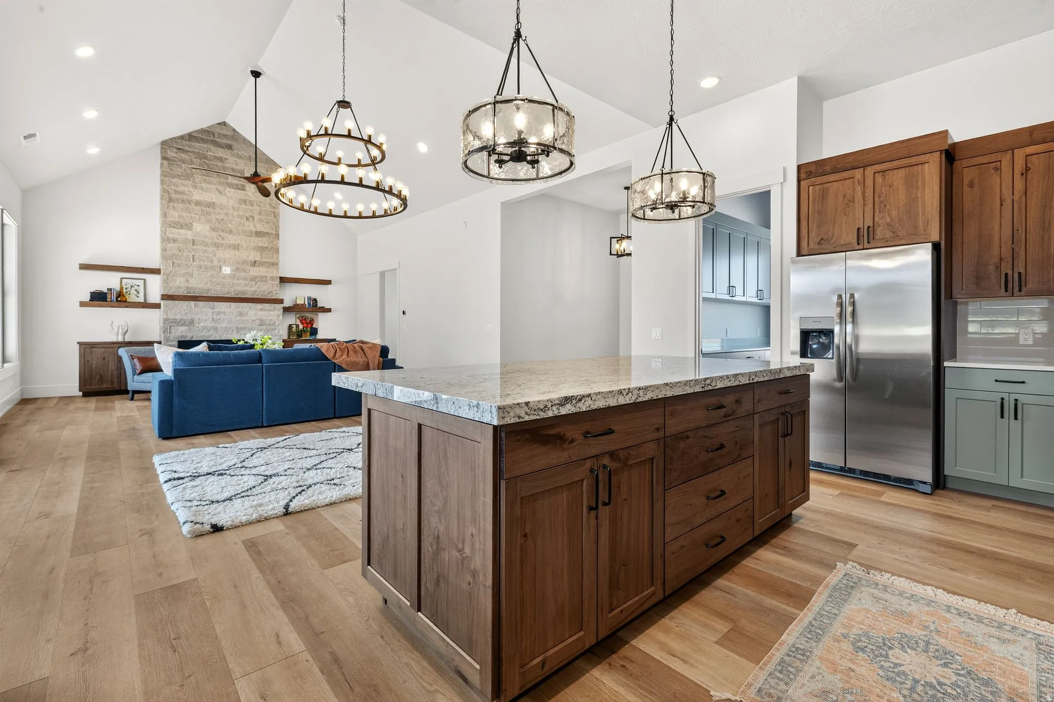 Spacious open-concept living area featuring wood-finish flooring, a vaulted ceiling, and recessed lighting
