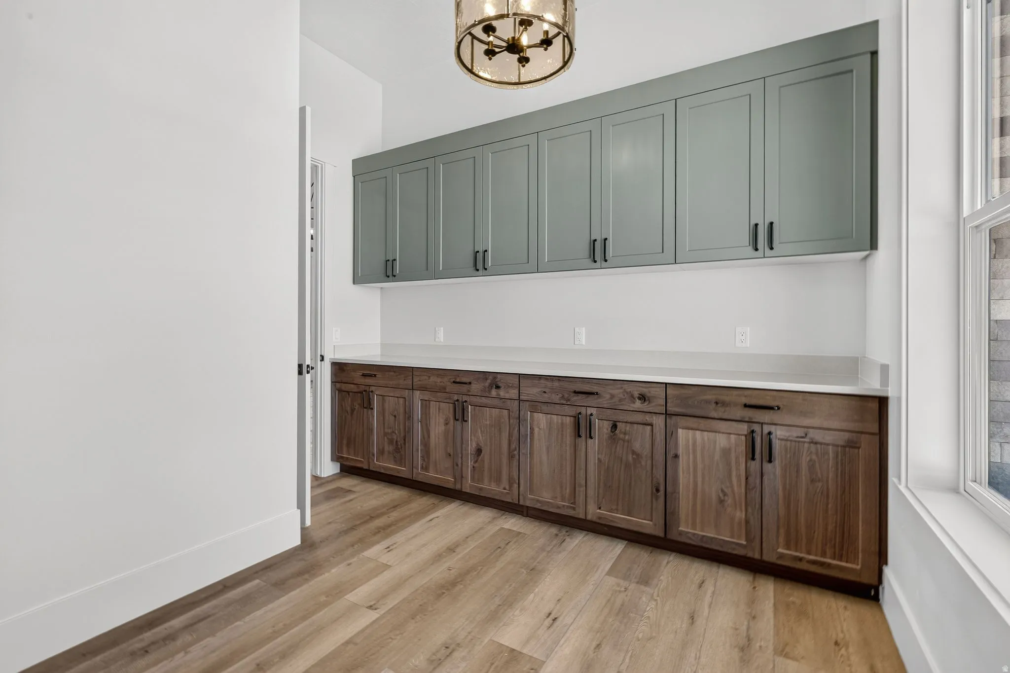 Walk-in oversized butler's pantry. Built-in cabinetry featuring wood-finish lower cabinets and sage upper cabinets with matte black hardware