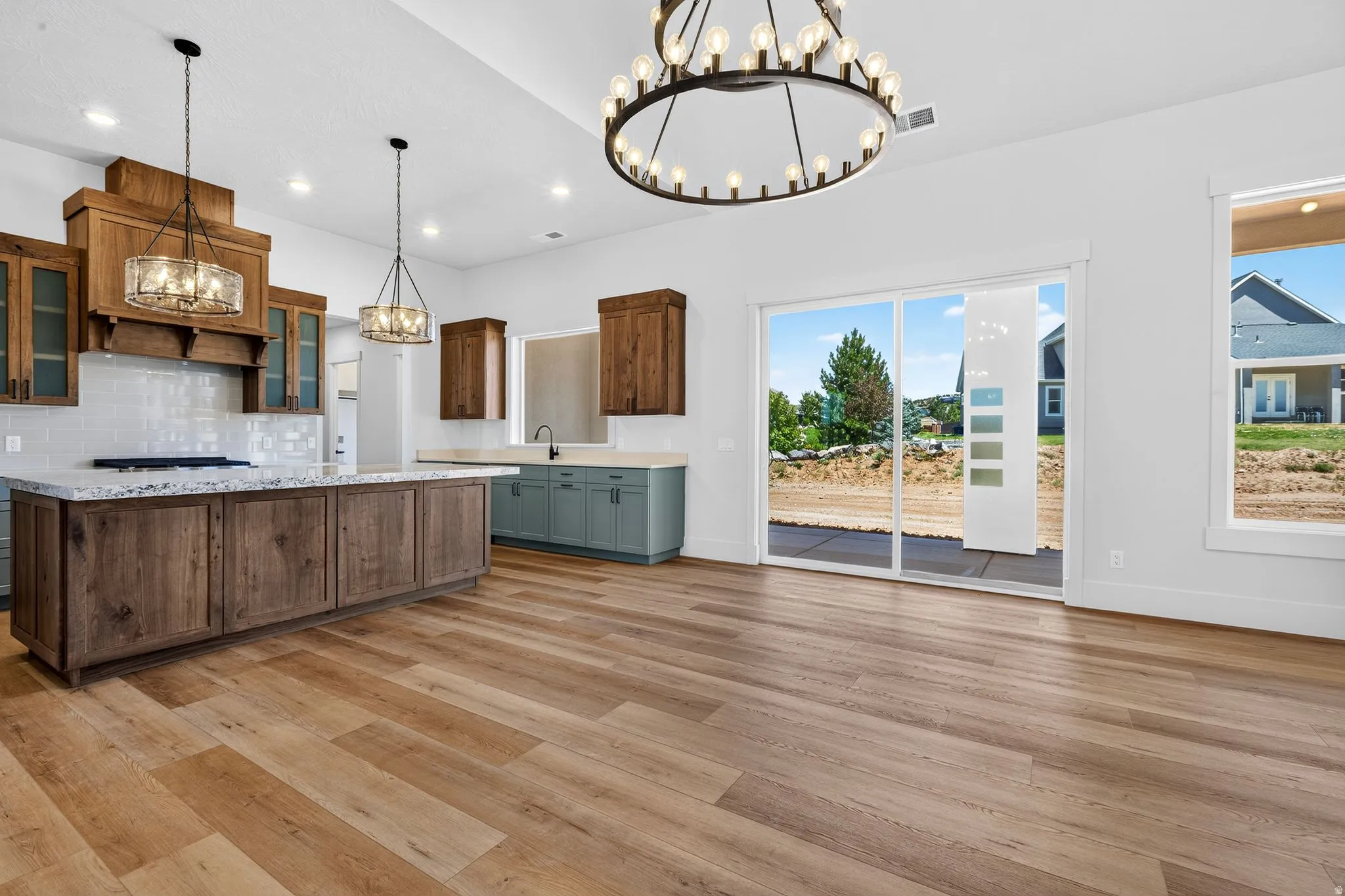 Open-concept kitchen and living area featuring laminate flooring, a large kitchen island with a light-colored countertop, and a white subway tile backsplash