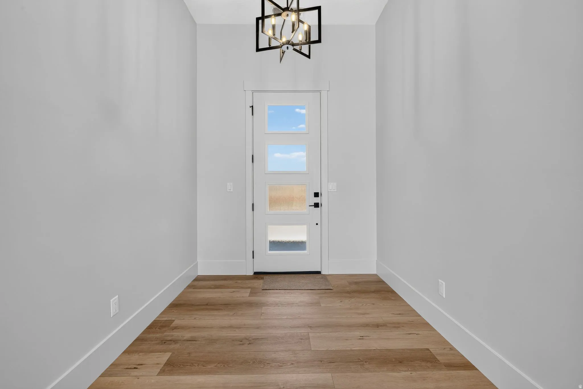 Entryway featuring wood-finish flooring and a contemporary chandelier