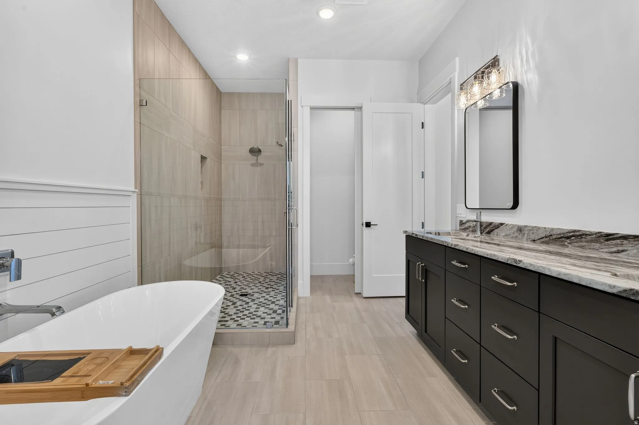 Freestanding soaking tub and glass-enclosed shower with tiled walls and floor