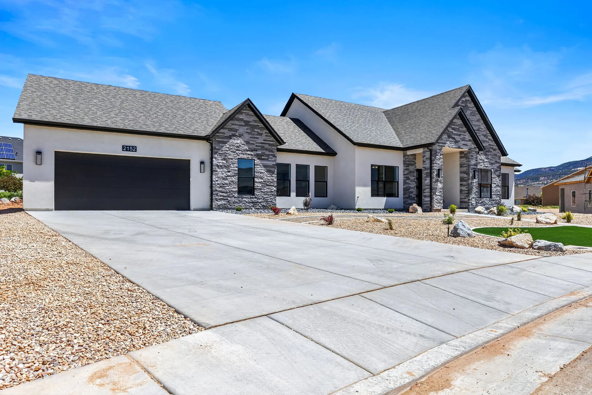 Contemporary exterior featuring a white stucco facade and dark grey stone accents