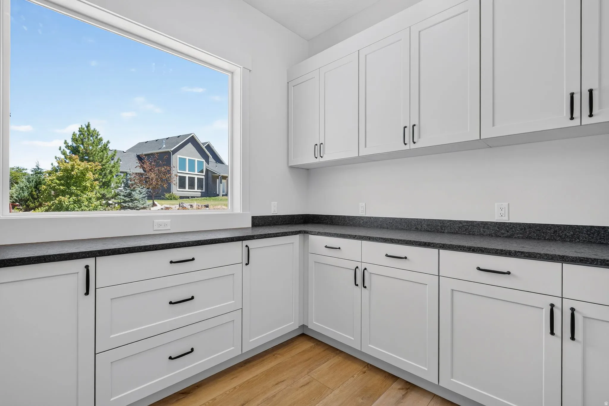 Spacious laundry room featuring extensive cabinetry, dark speckled countertops, and laminate flooring