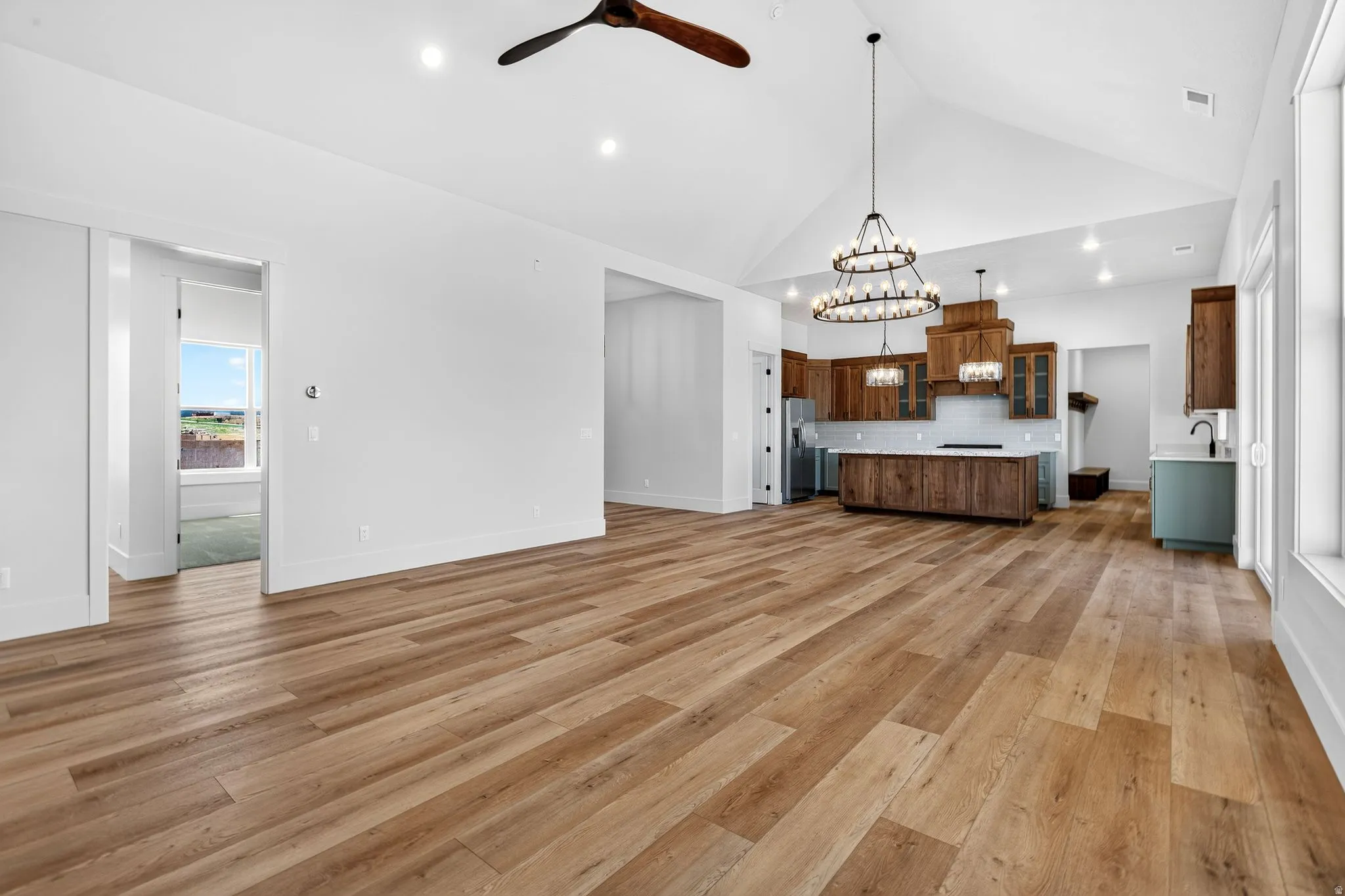 Vaulted great room featuring laminate flooring, recessed lighting, and a modern ceiling fan