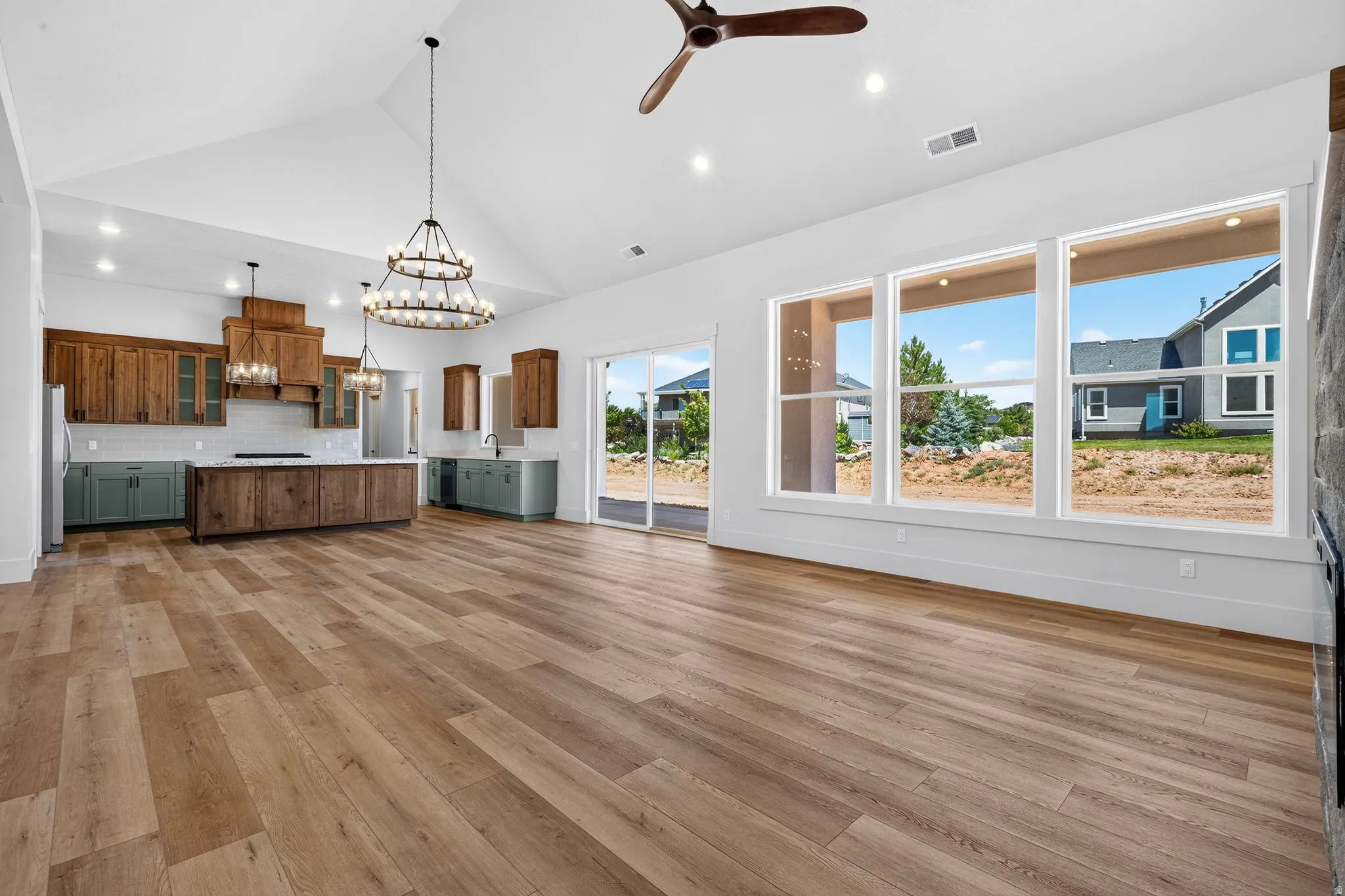 Open-concept living area featuring laminate flooring, vaulted ceilings, and a kitchen with two-tone cabinetry