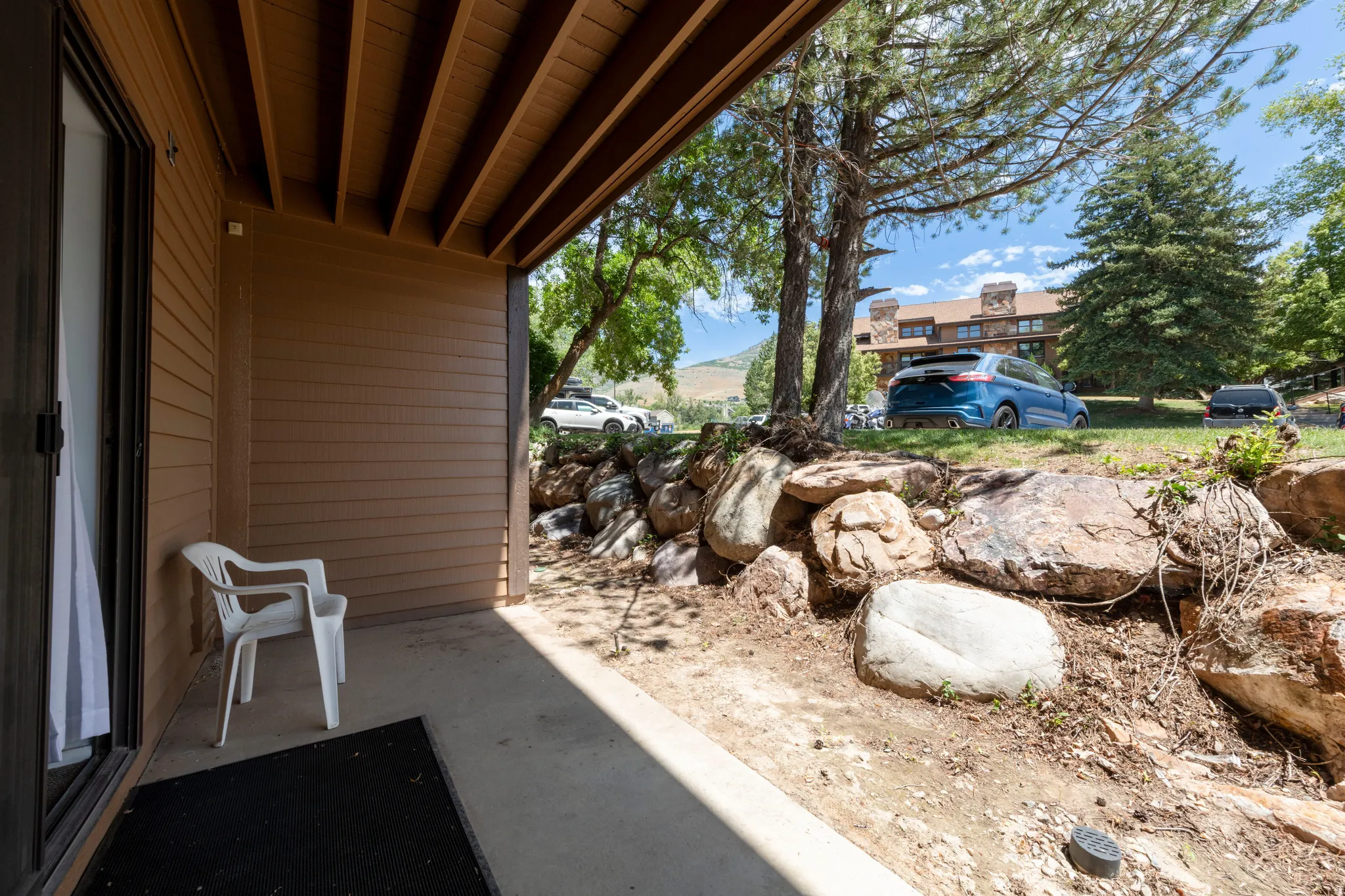 Covered patio area with concrete flooring, brown siding, and an exposed wooden beam ceiling