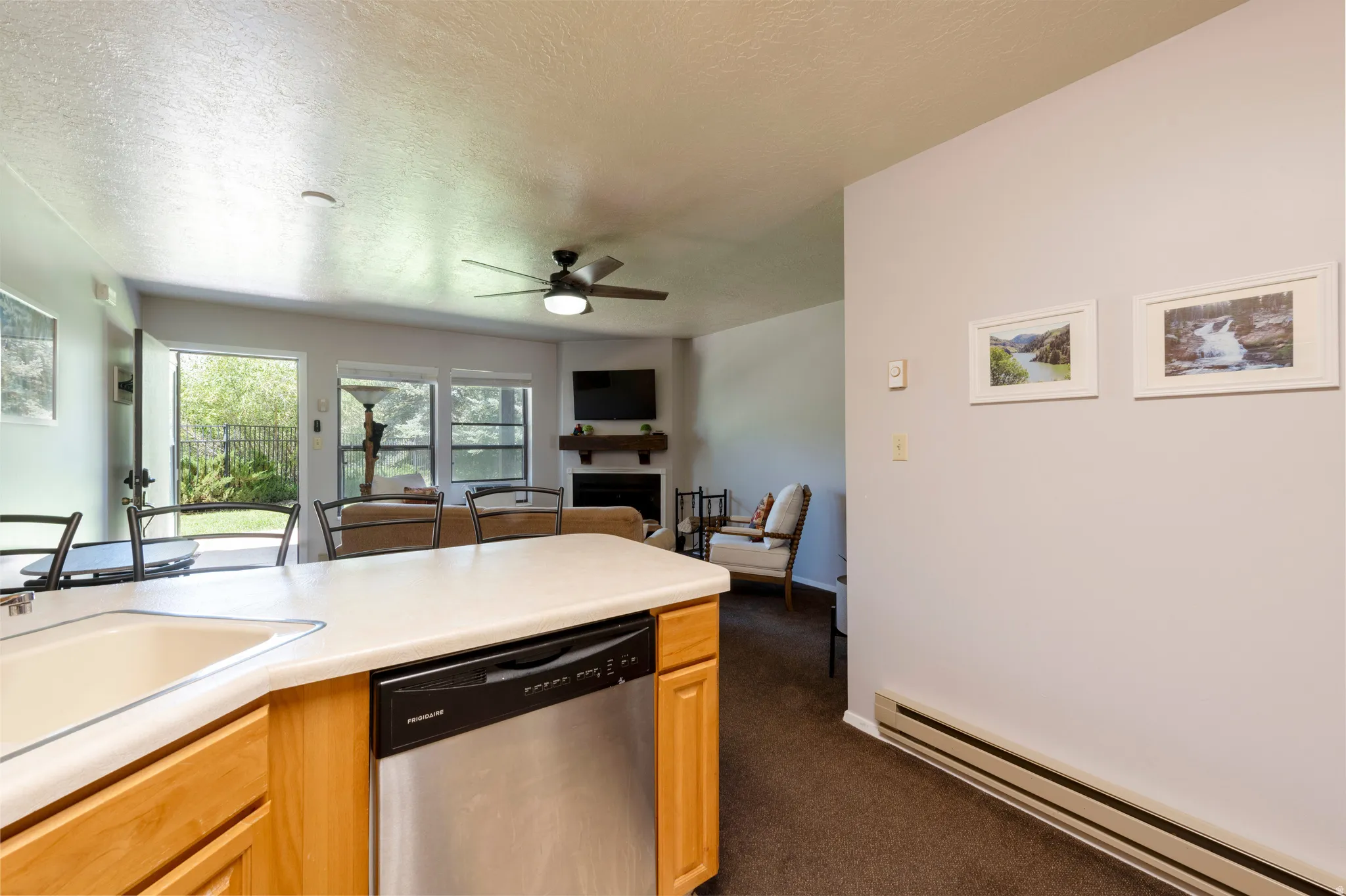 Open-concept living space featuring a kitchen island with integrated sink, stainless steel dishwasher, and light wood cabinetry