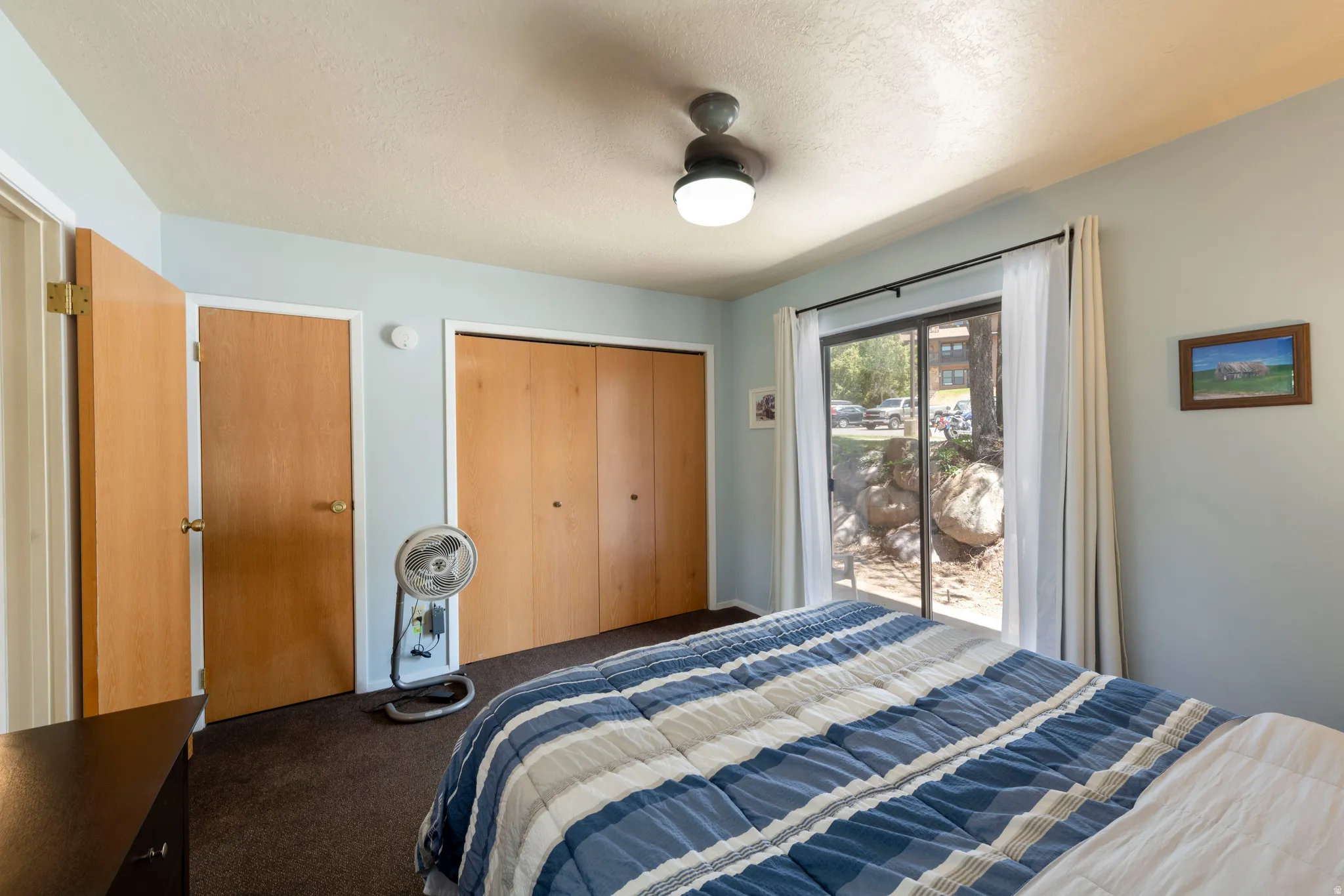 Sliding glass door access to exterior, ceiling fan with integrated lighting, wood-finish bi-fold closet doors, and wood-finish interior doors