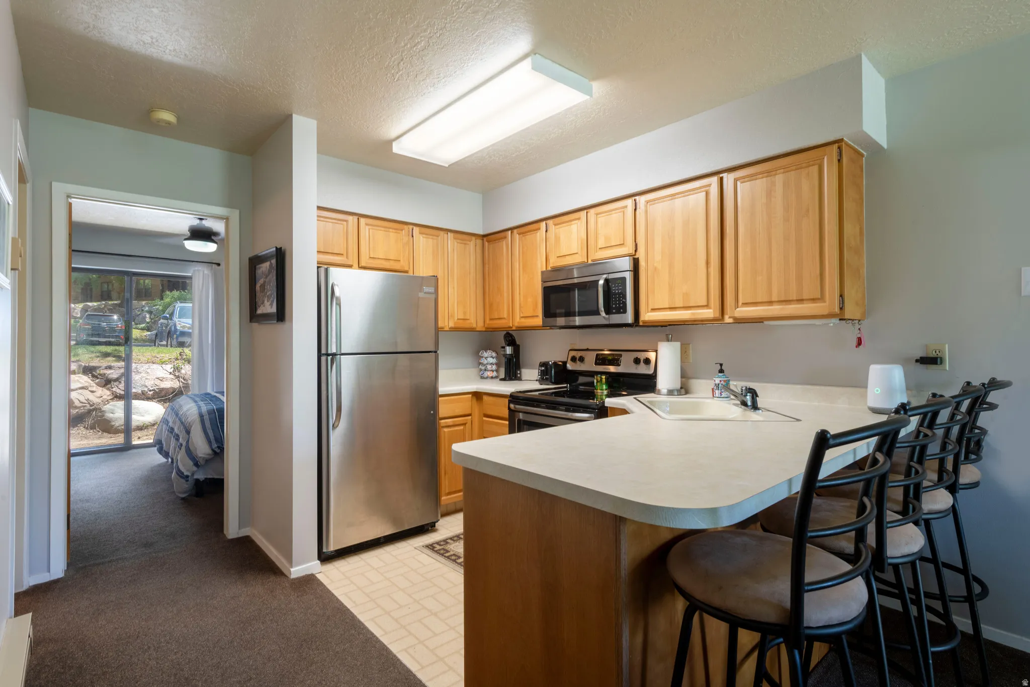 Kitchen featuring wood cabinetry, stainless steel appliances, a light-toned countertop, and an integrated breakfast bar
