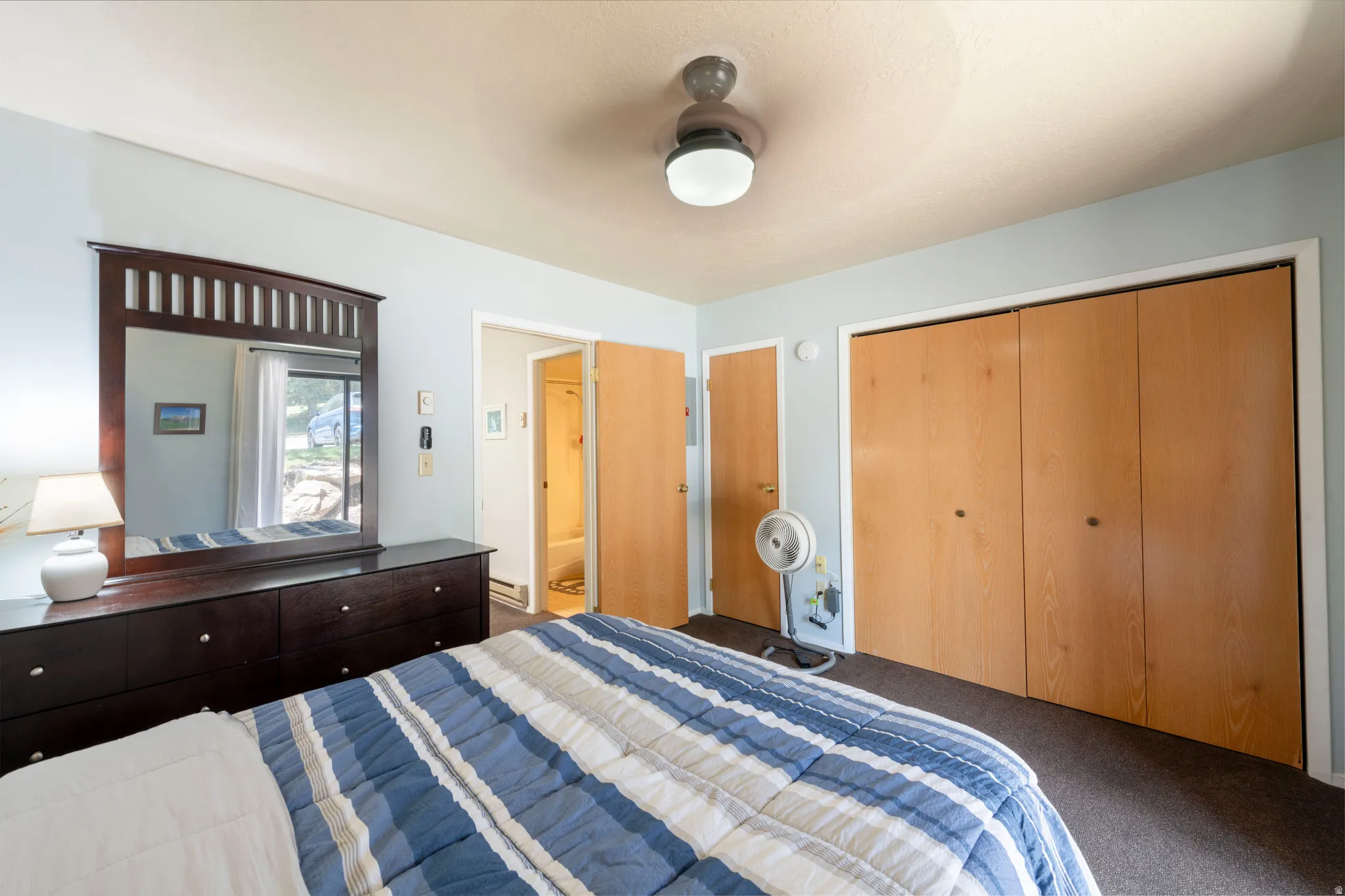 Bedroom featuring a ceiling fan, light blue walls, and a window with outdoor scenery