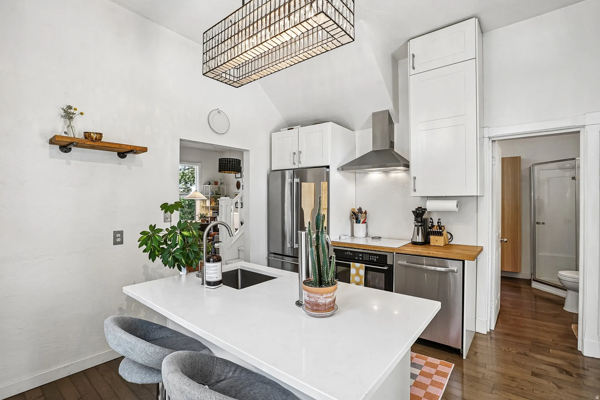 Modern kitchen featuring white shaker cabinetry, stainless steel appliances, butcher block countertops, and a central island with a built-in sink and seating