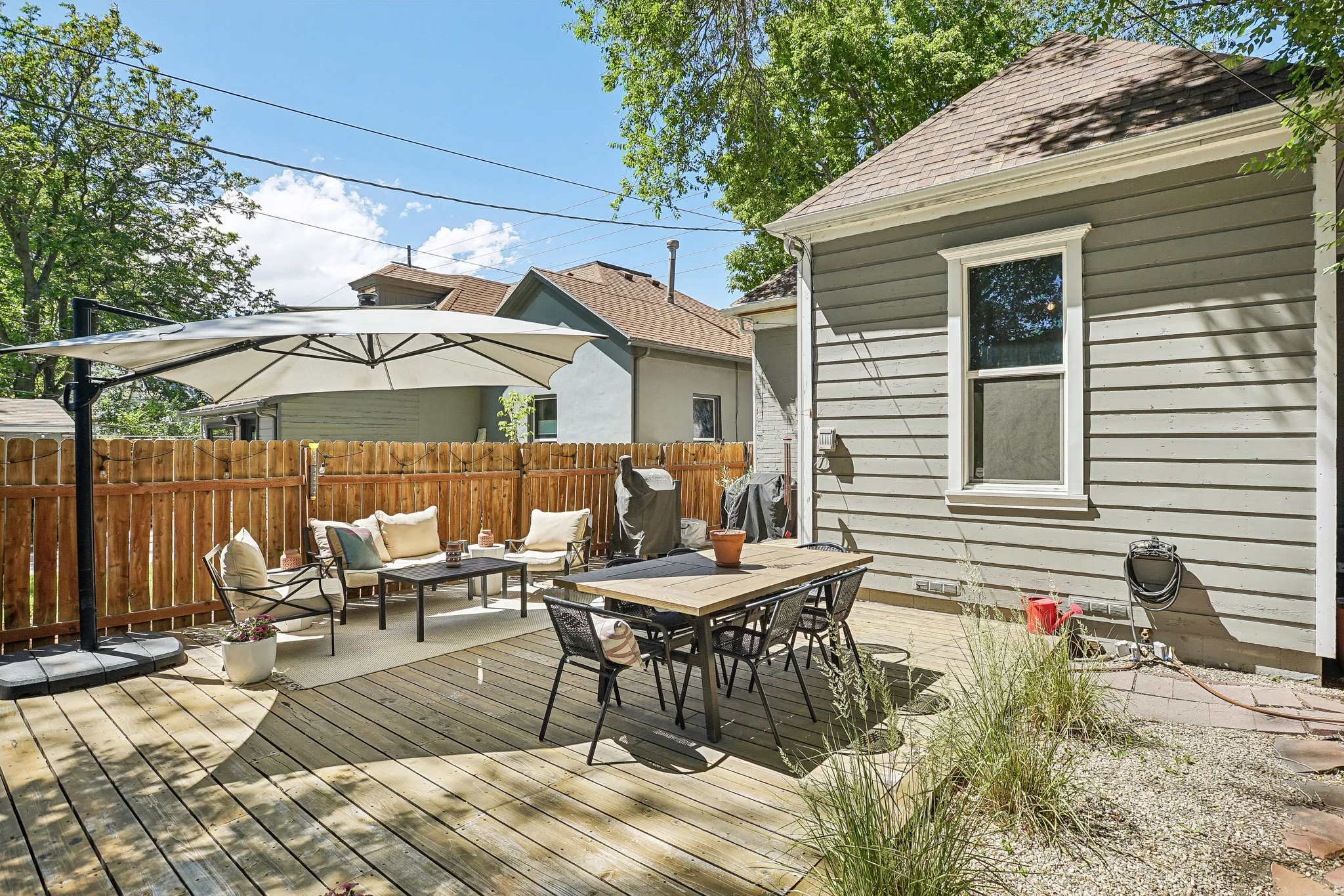 Expansive wood deck with plank flooring, featuring a dedicated dining area and a distinct lounge area